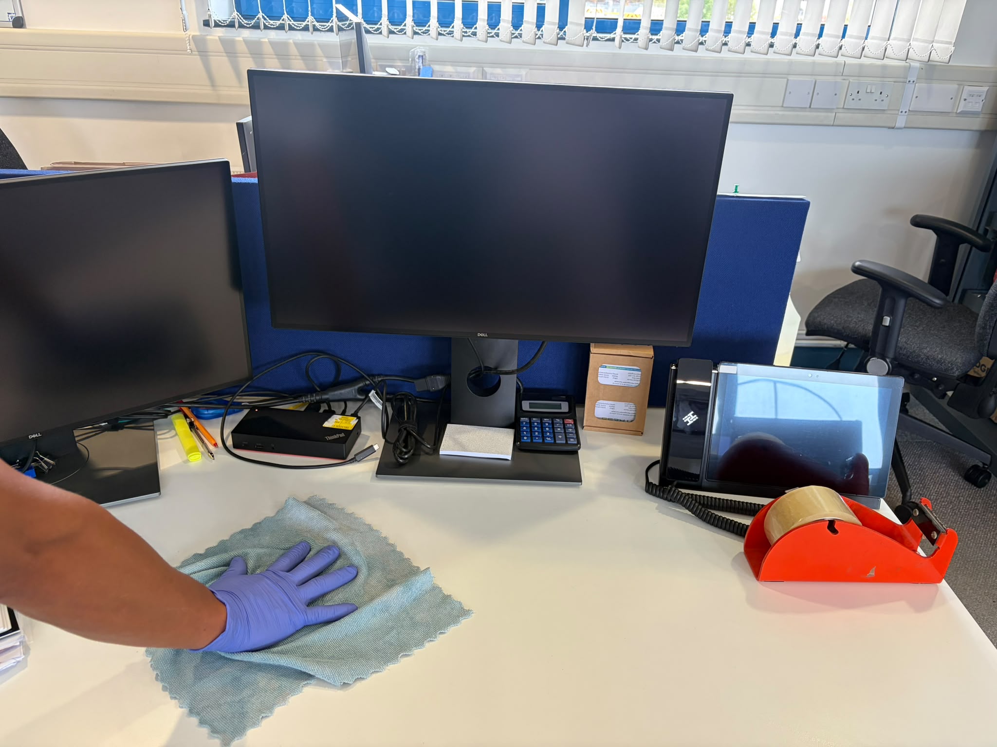 Office desk and workspace being cleaned and sanitised with a microfiber cloth