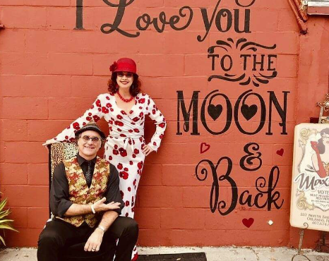 Kirt and Maxine Earhart in front of 'I Love You to the Moon & Back' mural at Maxine's On Shine