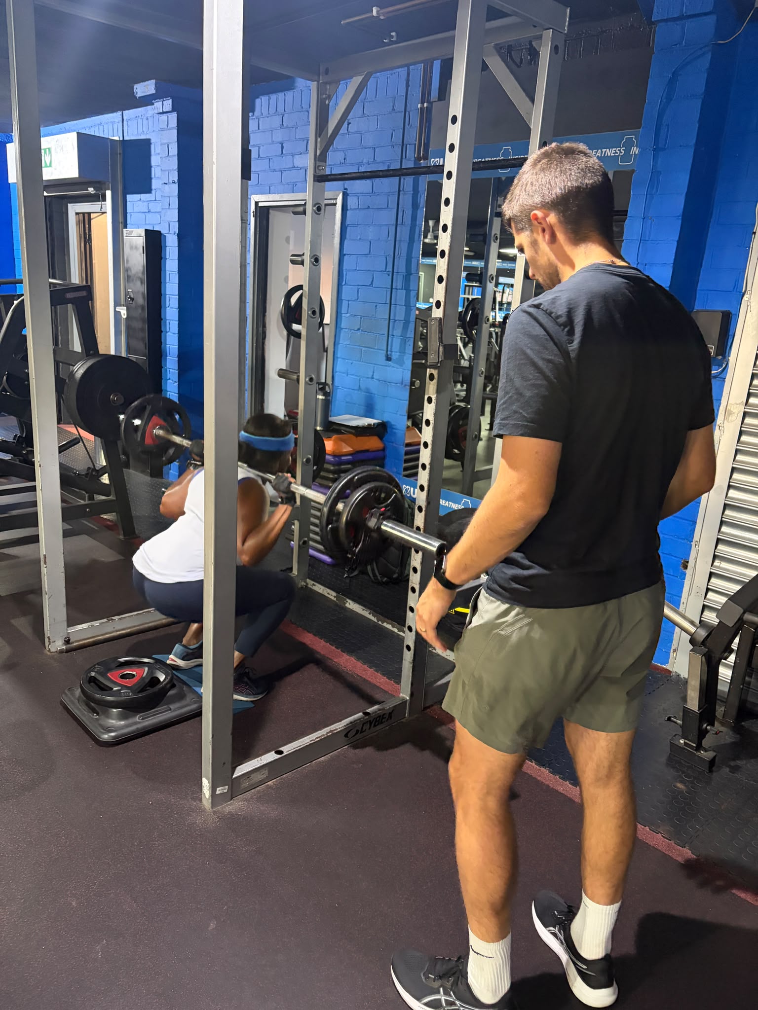 Dan coaching a client during a squat set at Energize Fitness