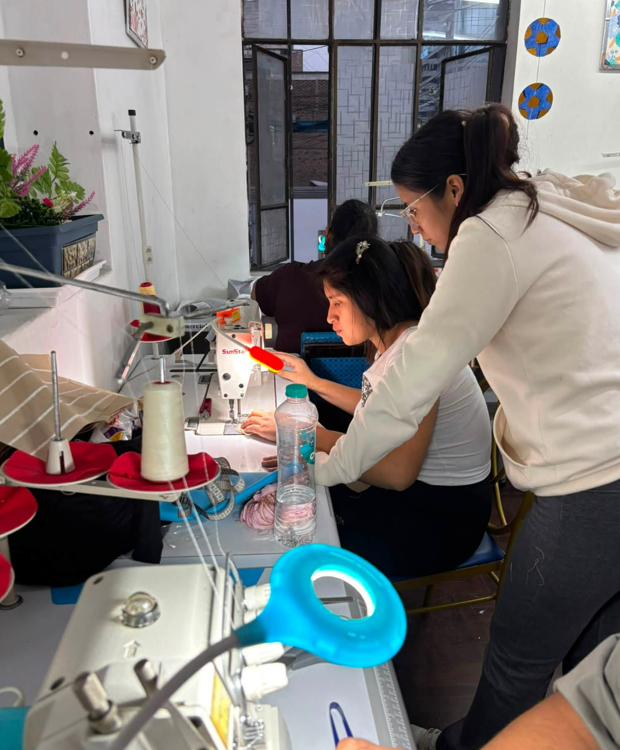Profesora guiando a alumna en máquina industrial en Apega Milenium