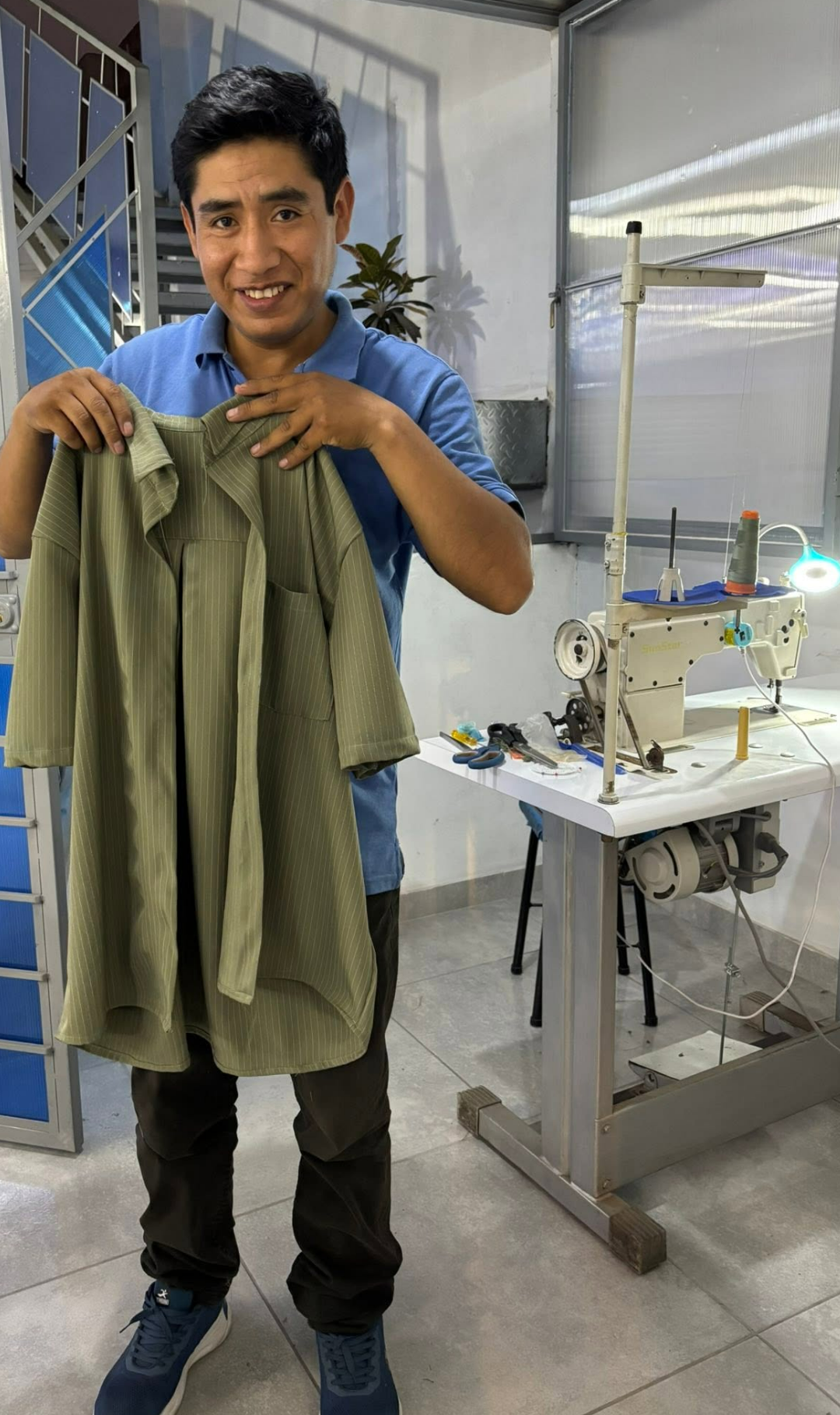Alumno emprendedor mostrando camisa terminada en su máquina