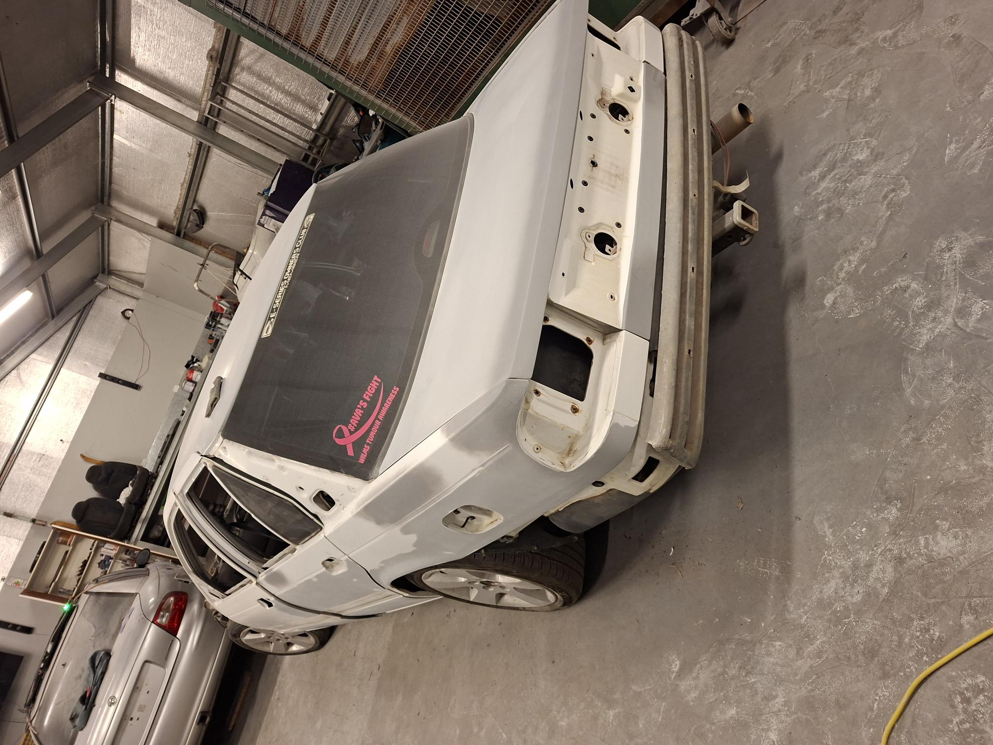 Rear quarter panels and beaver panel stripped of taillights and bumper with guide coat applied for block sanding in Horsham automotive paint workshop