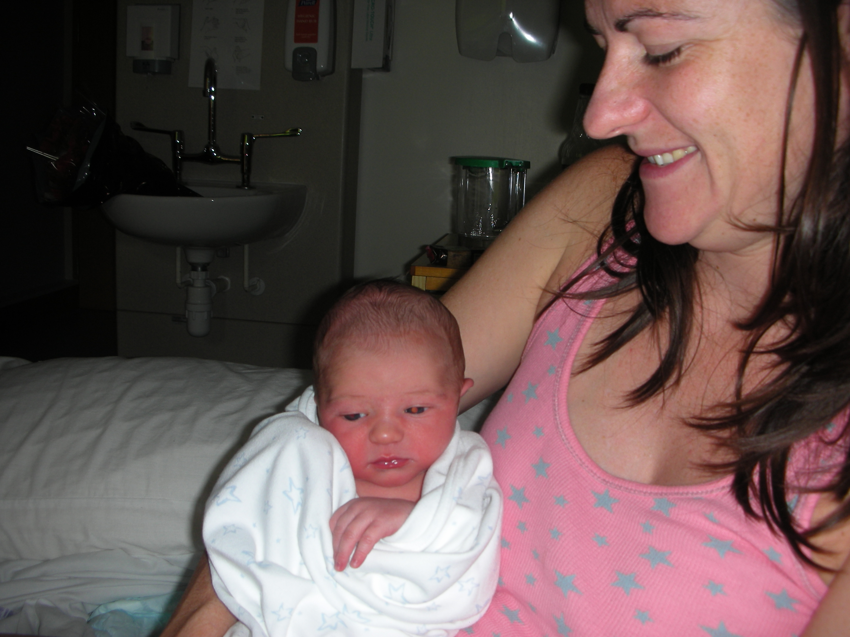 Lalena in hospital bed holding her firstborn baby boy wrapped in a starry blanket