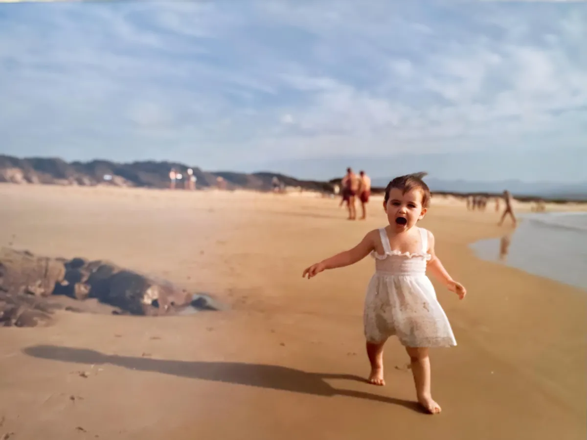 Lalena as a toddler running freely on a wide sunny beach