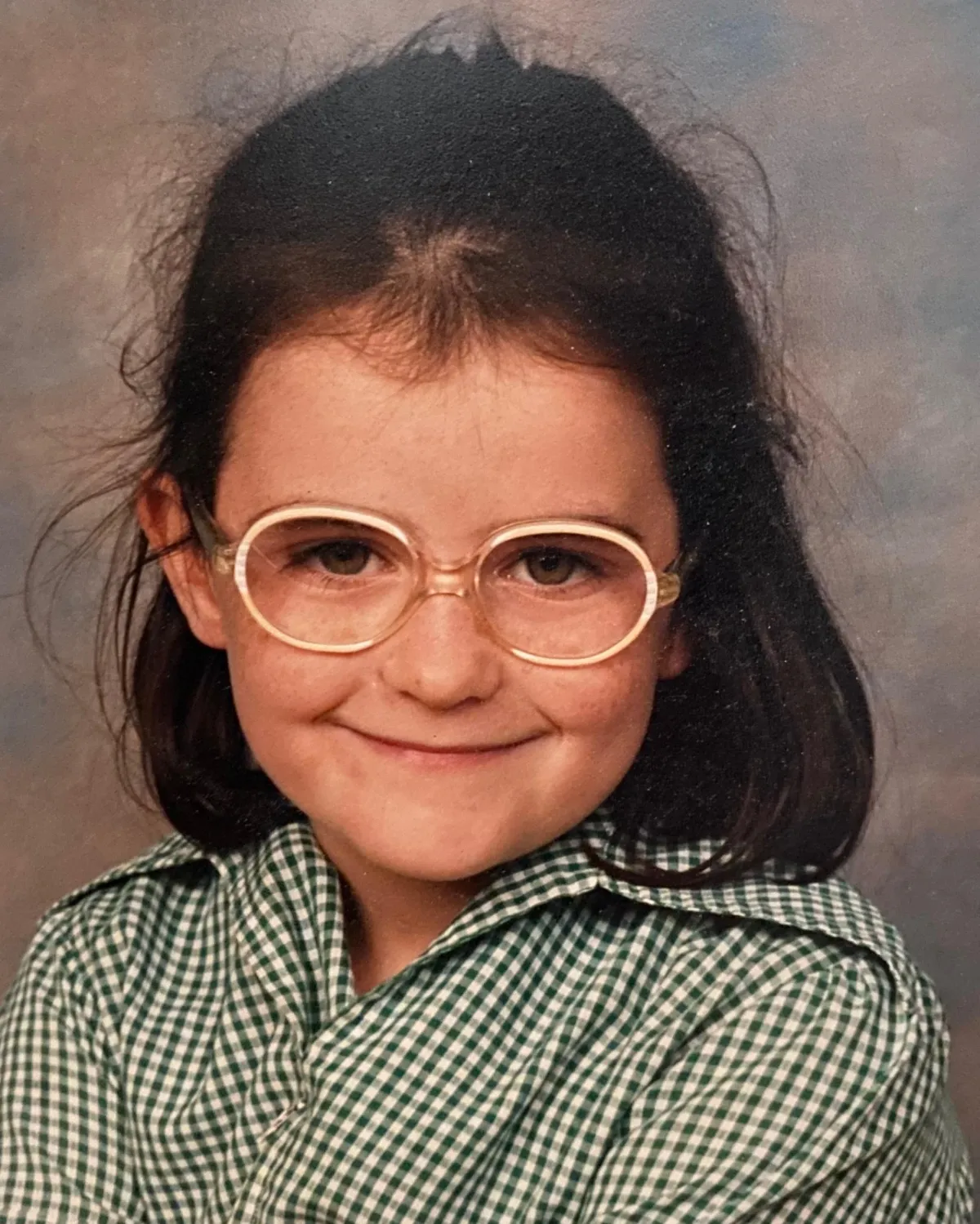 Young Lalena in school uniform and round glasses, smiling