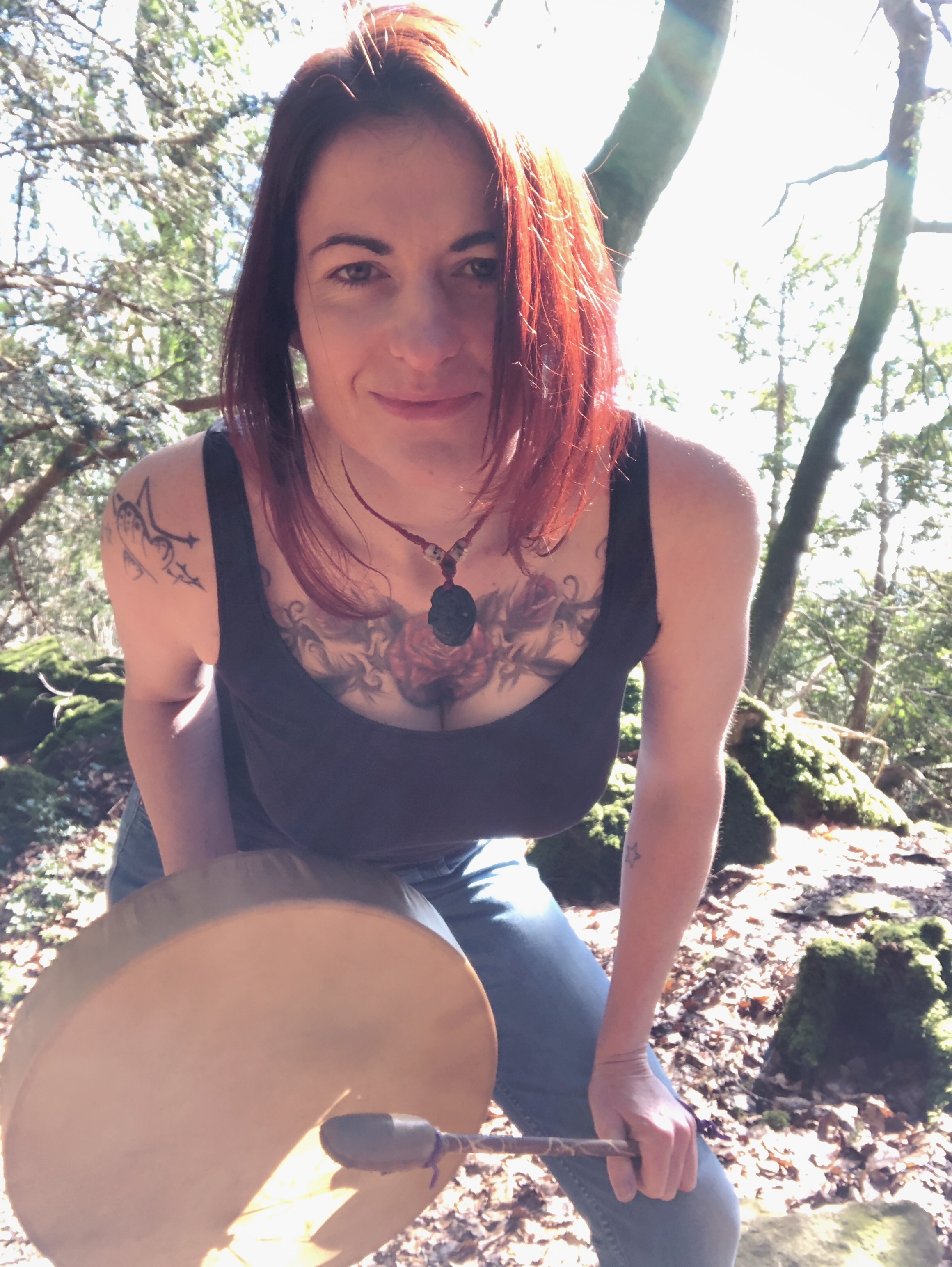 Lalena Rose in sunlit woods holding a frame drum