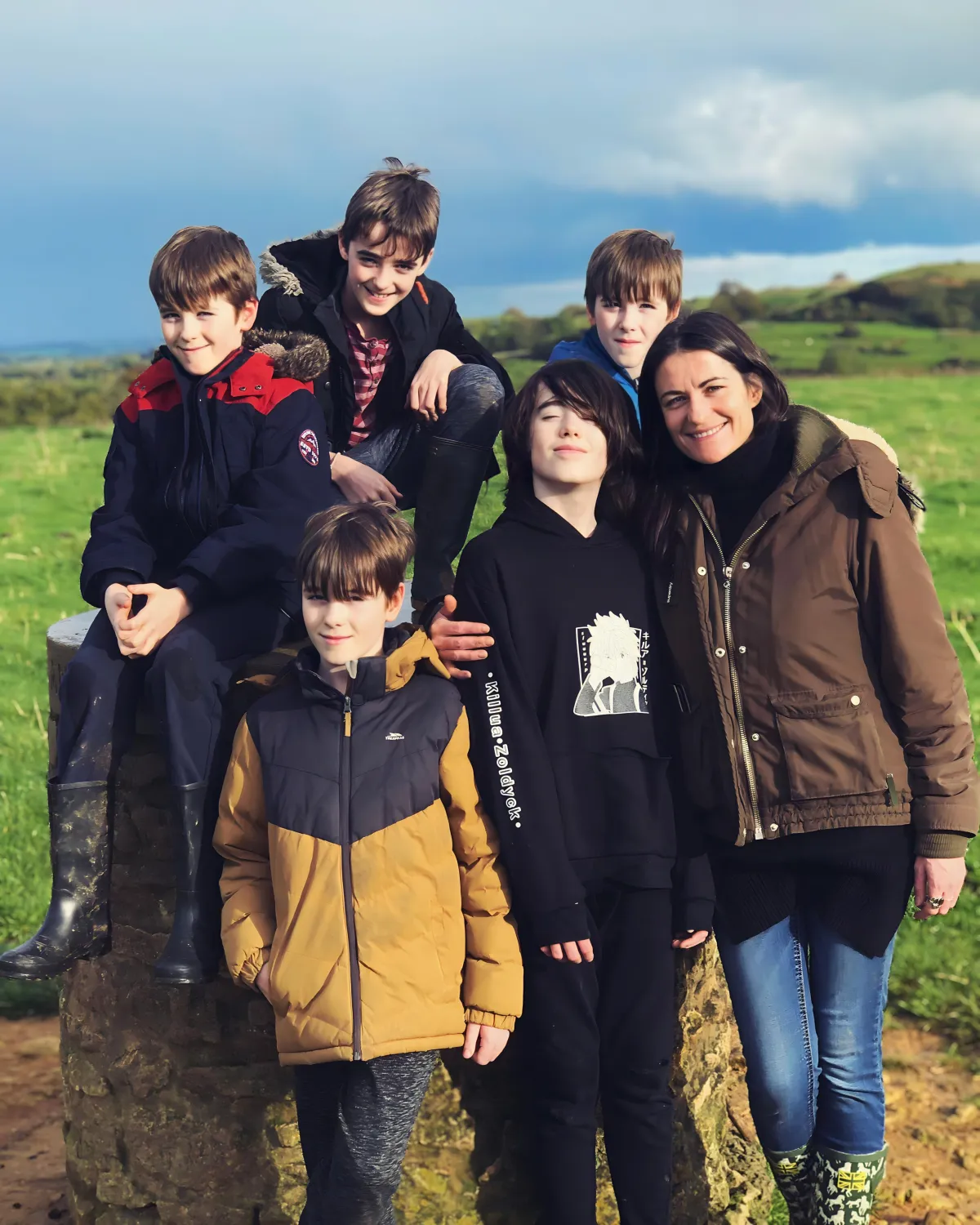 Lalena Rose smiling outdoors in the green Welsh countryside surrounded by her five sons