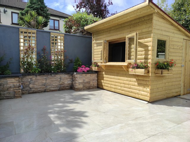 Garden patio with stone feature wall and wooden summer cabin completed by Multi Purpose Home Improvements
