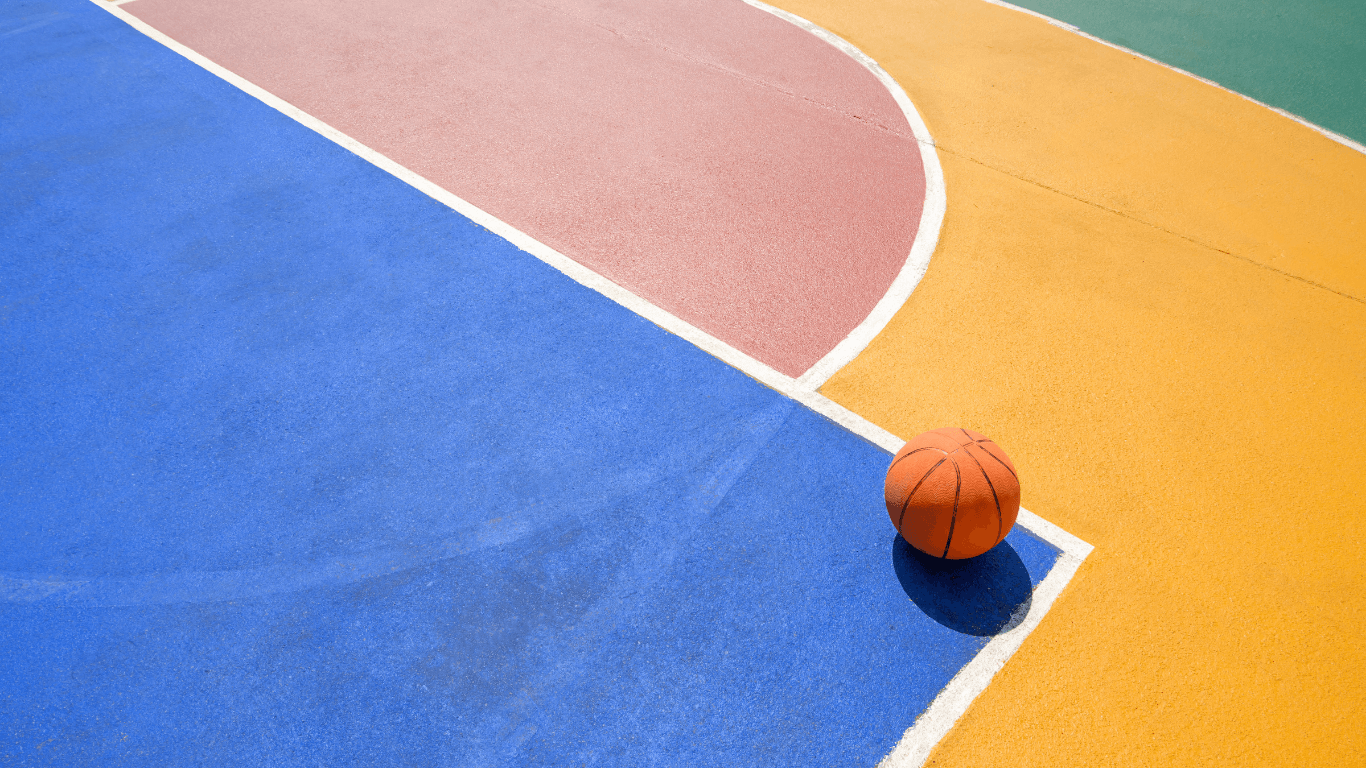 Close-up of a colorful basketball court surface with blue, yellow, and red painted sections during a court builder service in Henderson, NV