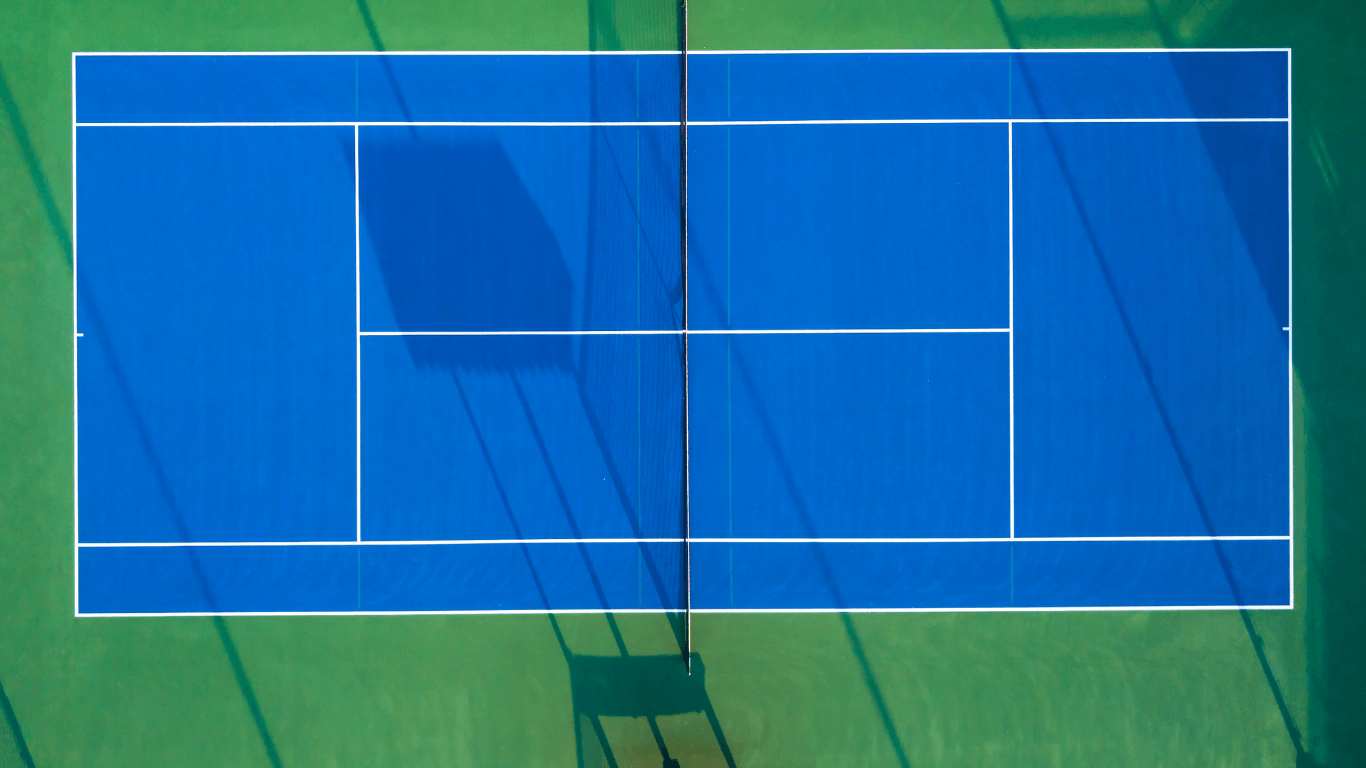 Players standing on a bright blue indoor pickleball court with glass walls after a court builder service in Henderson, NV