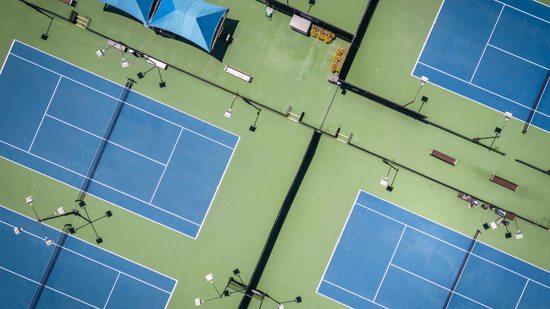 Aerial view of multiple blue tennis courts inside a large recreational complex during a court builder service in Henderson, NV
