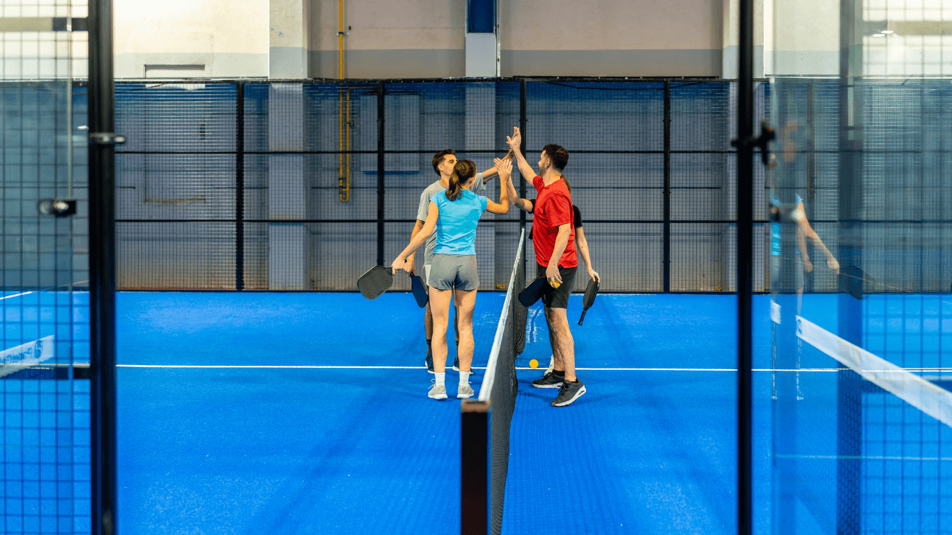 Close-up of a pickleball paddle and yellow ball on a blue textured playing surface during a court builder service in Henderson, NV