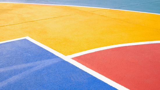 Bright sport court surface with bold yellow, blue, and red sections and smooth painted lines during a court builder service in Henderson, NV