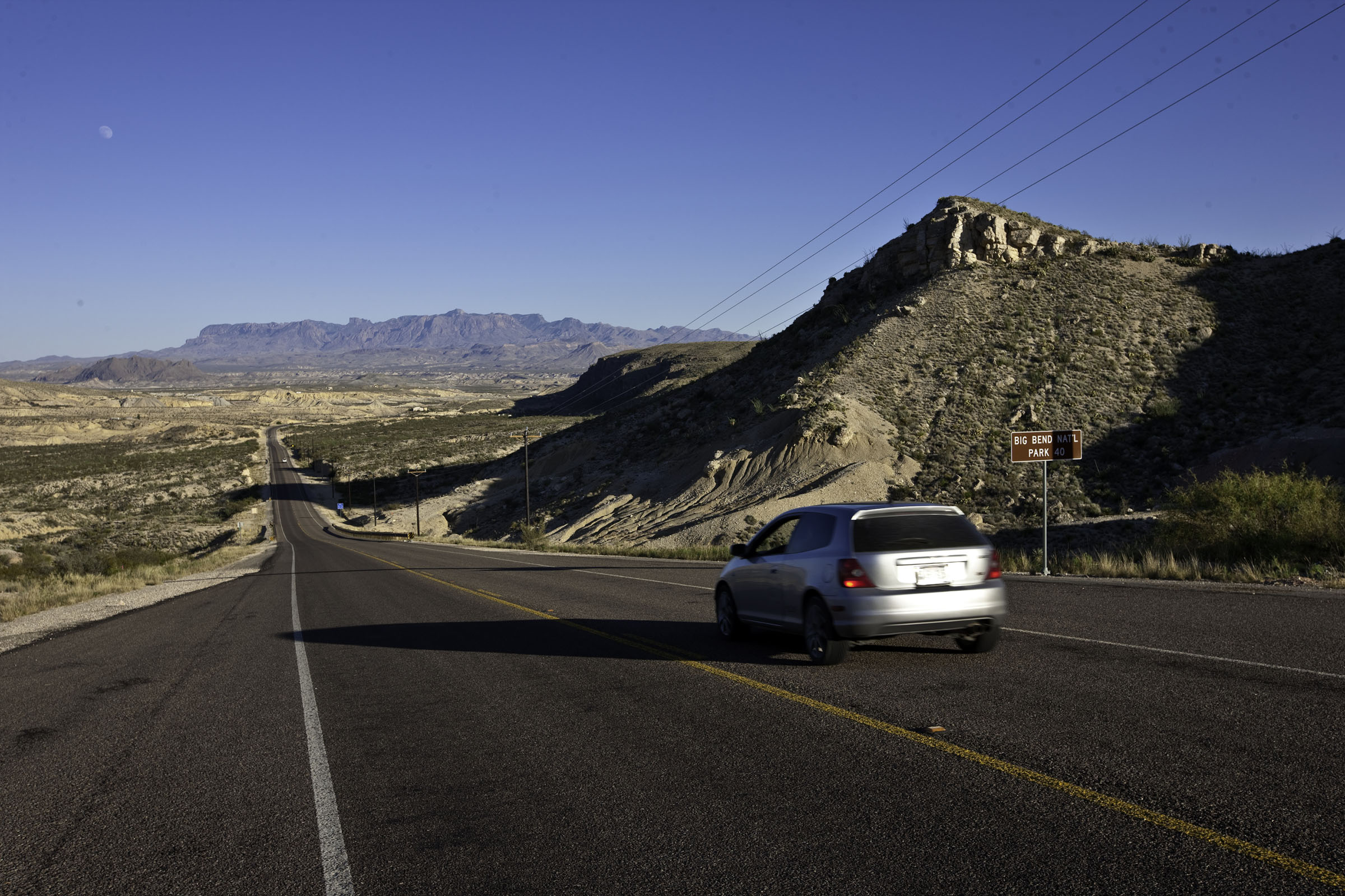 Silver car driving on scenic Texas highway toward Big Bend National Park