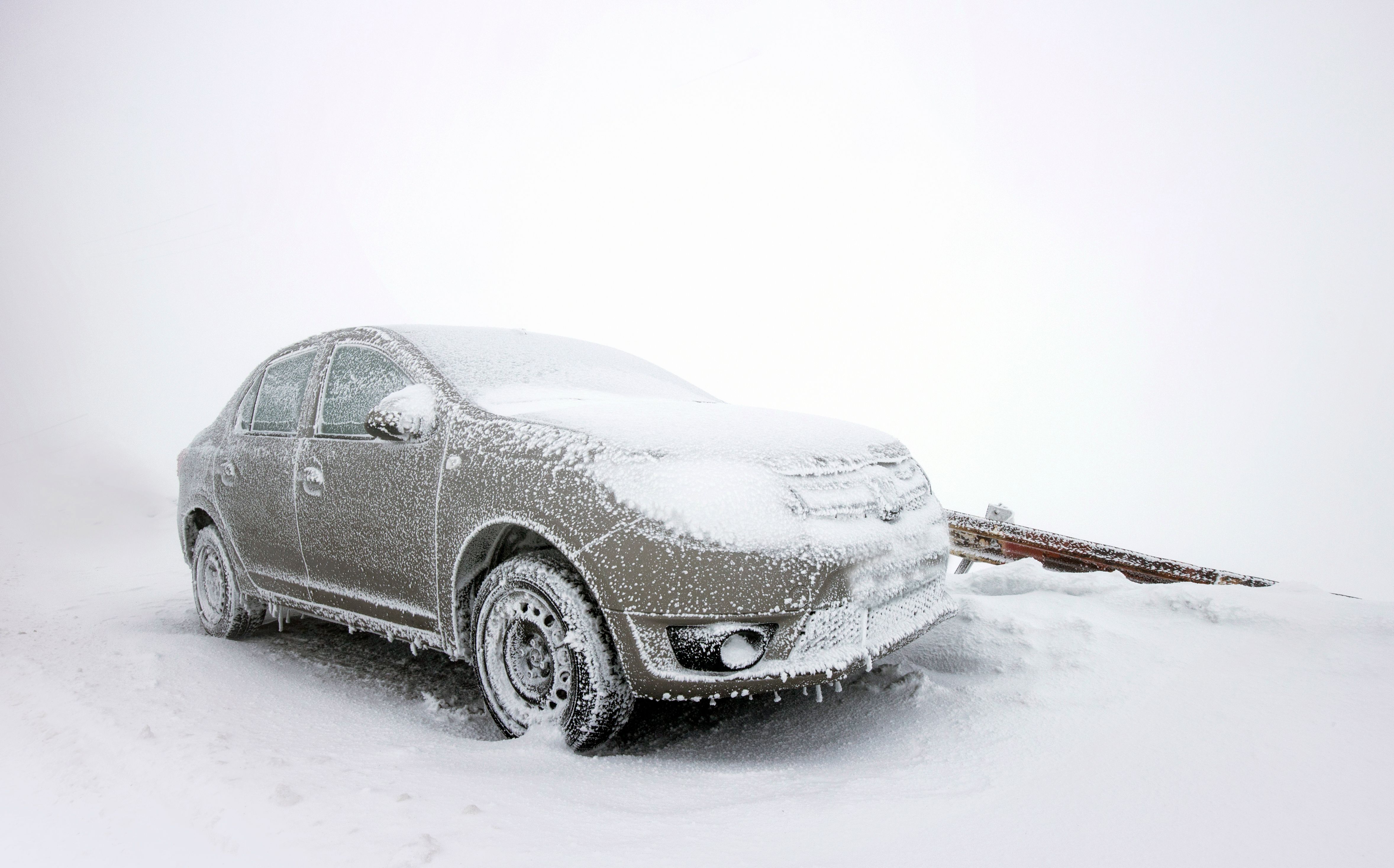 Car covered in snow and winter road salt buildup