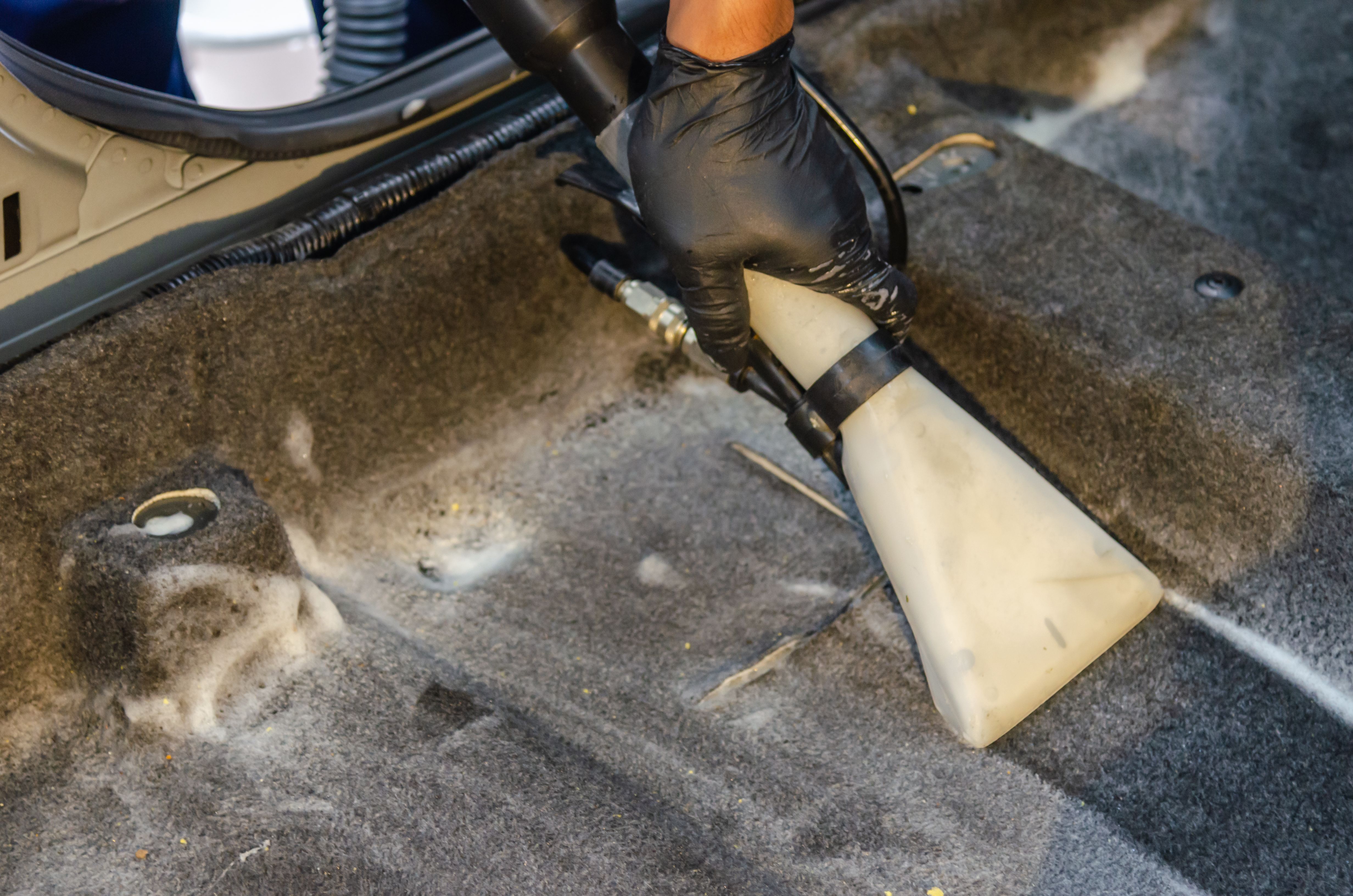 Professional carpet extractor cleaning deeply embedded dirt and salt residue from automotive carpet