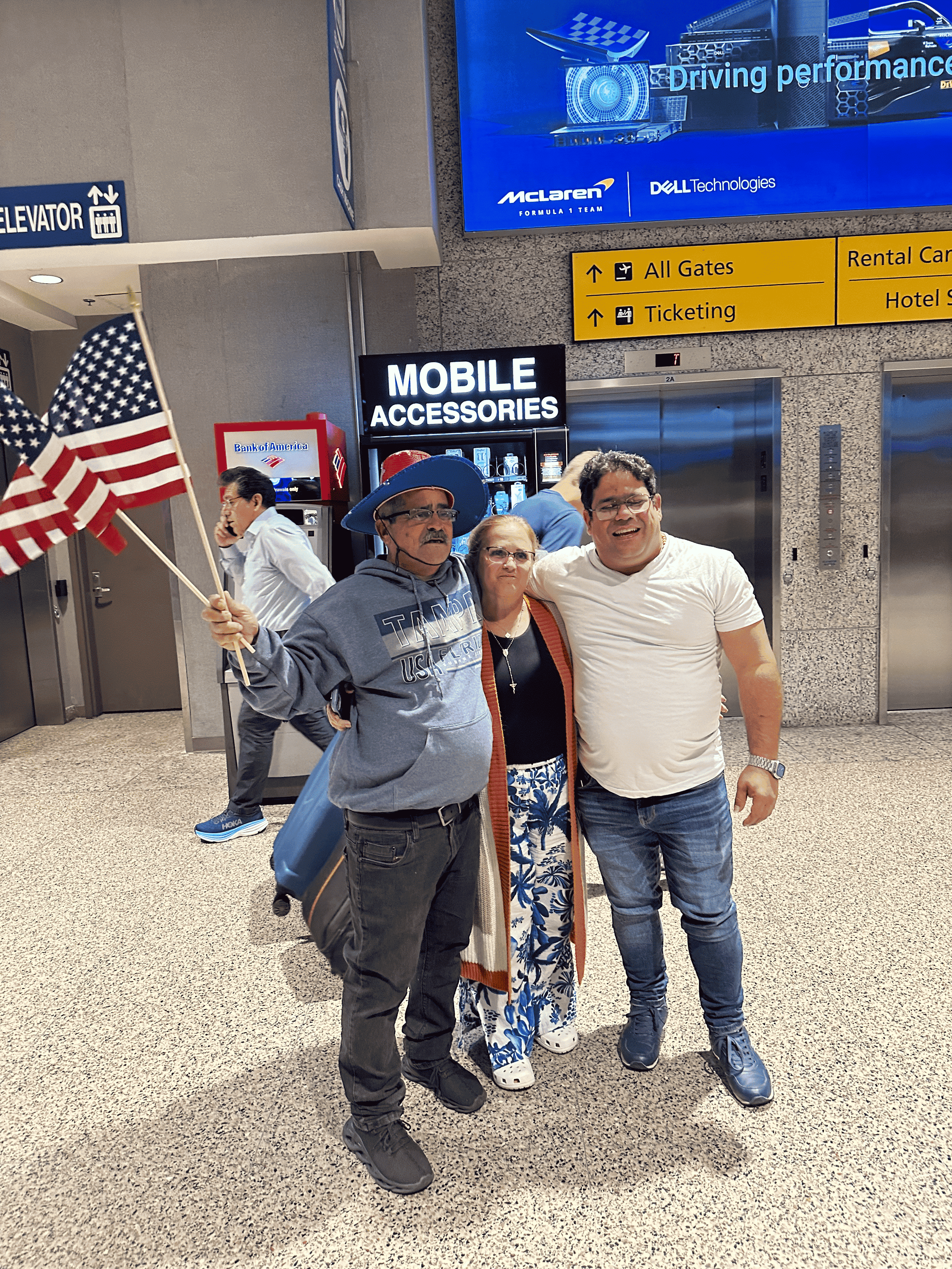 Familia recibiendo a sus seres queridos en el aeropuerto con banderas de Estados Unidos