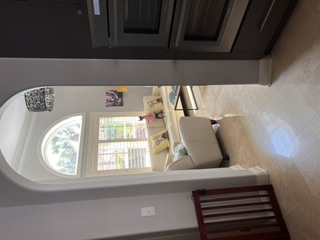 Front Window Surveillance: Framed through the kitchen archway, Pixie posted atop the sofa cushions peering out the plantation shutters on squirrel and intruder alert.