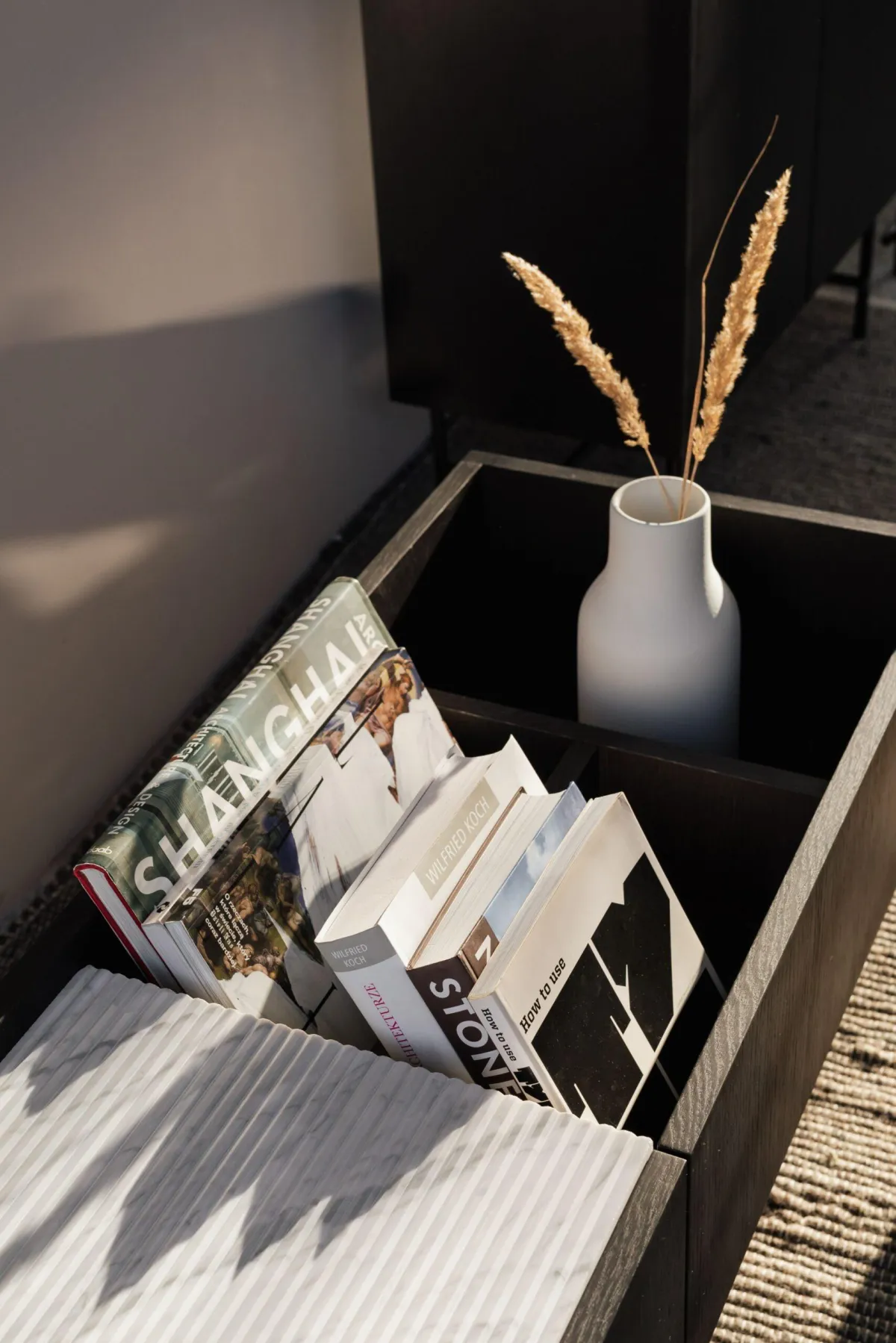 Books and white vase in a wooden tray