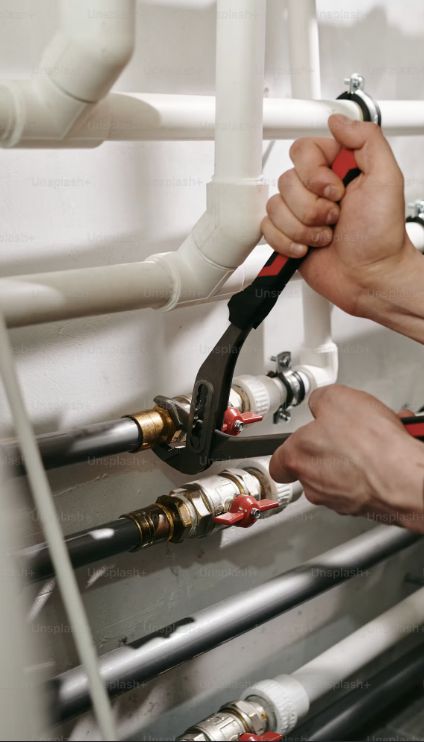 Hands of a professional plumber tightening residential pipe valves with a wrench