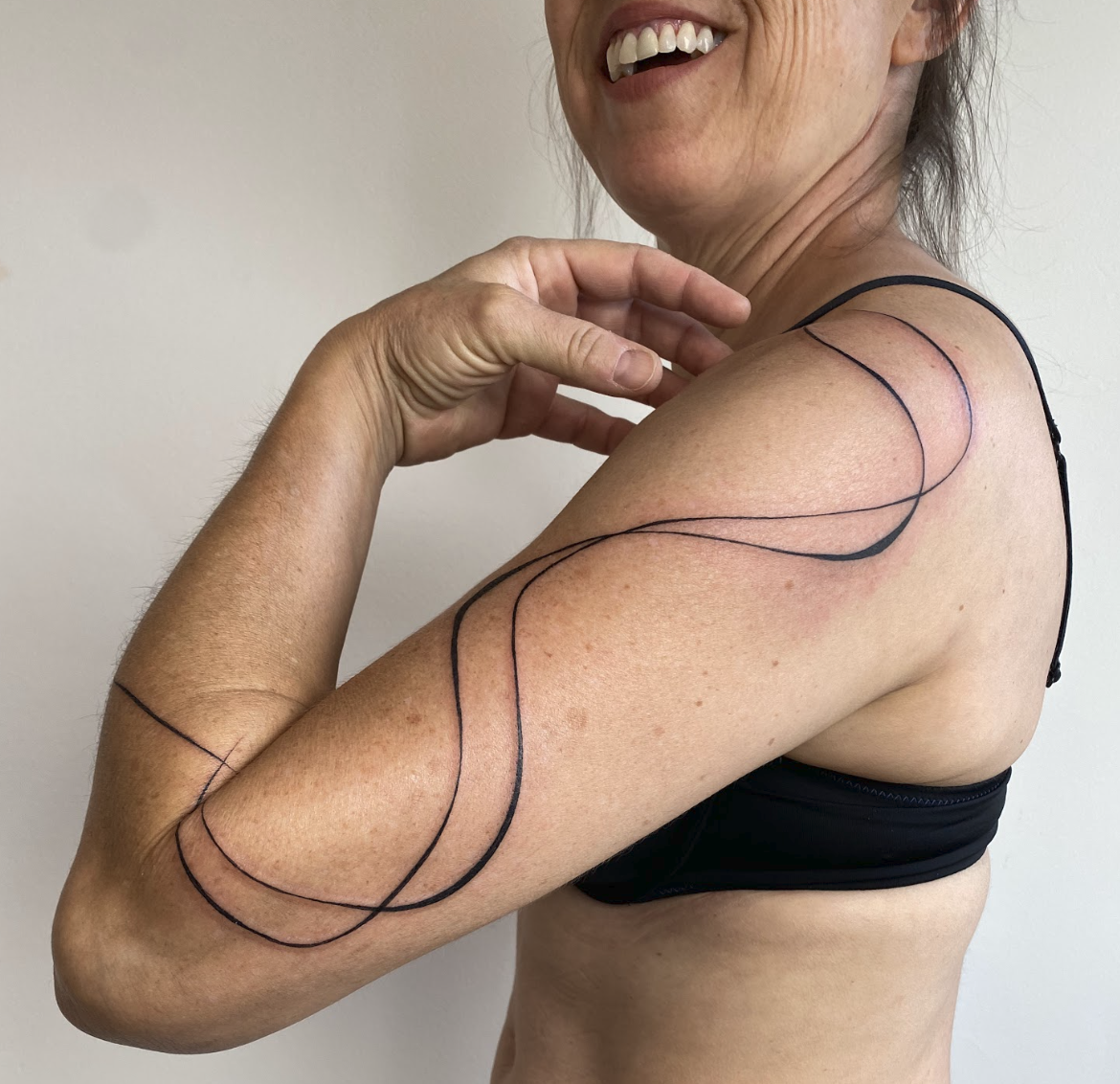 Minimalist Harmonic Energy Wave & Ribbon Arm Tattoo by Justine Almaraz