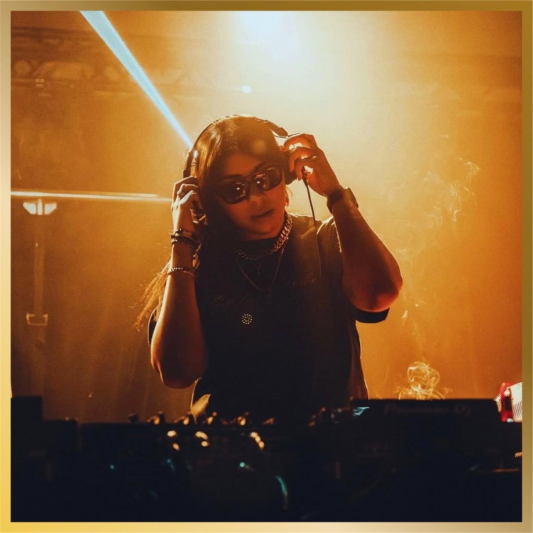 DJ performing under warm gold stage lights at McQueens