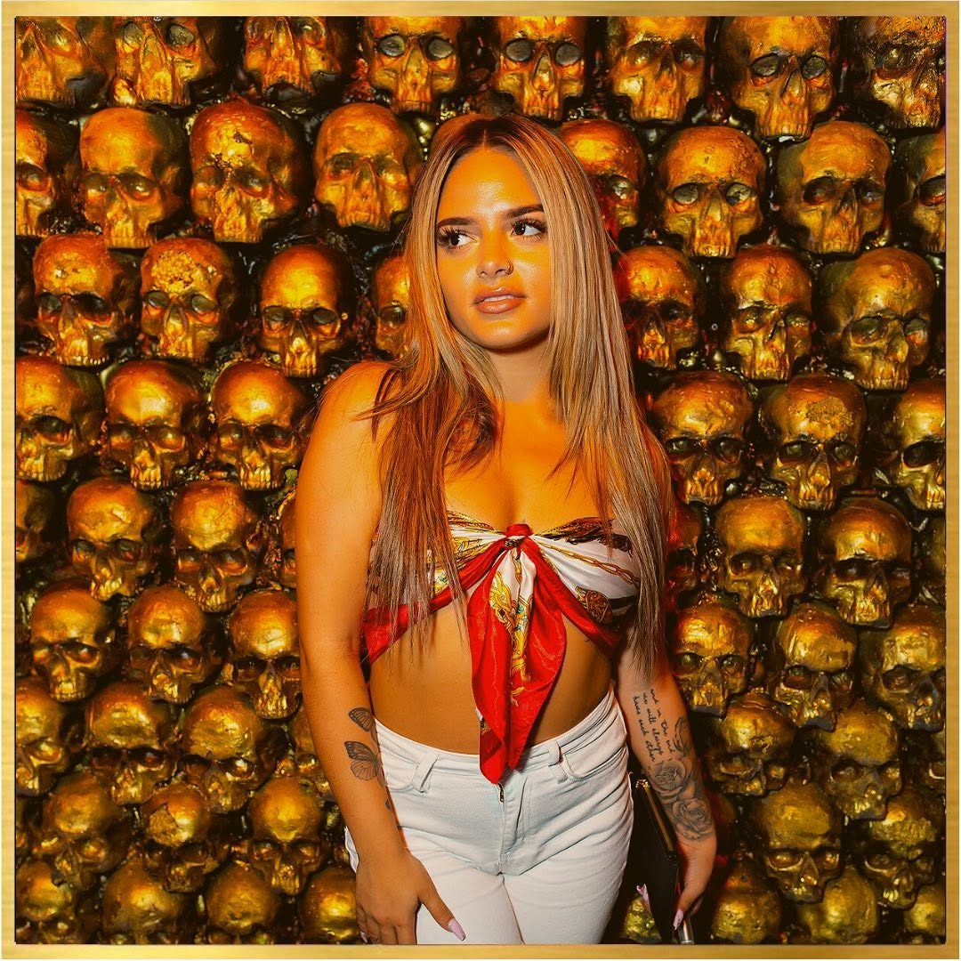 Guest posing by the iconic gold skull wall at McQueens
