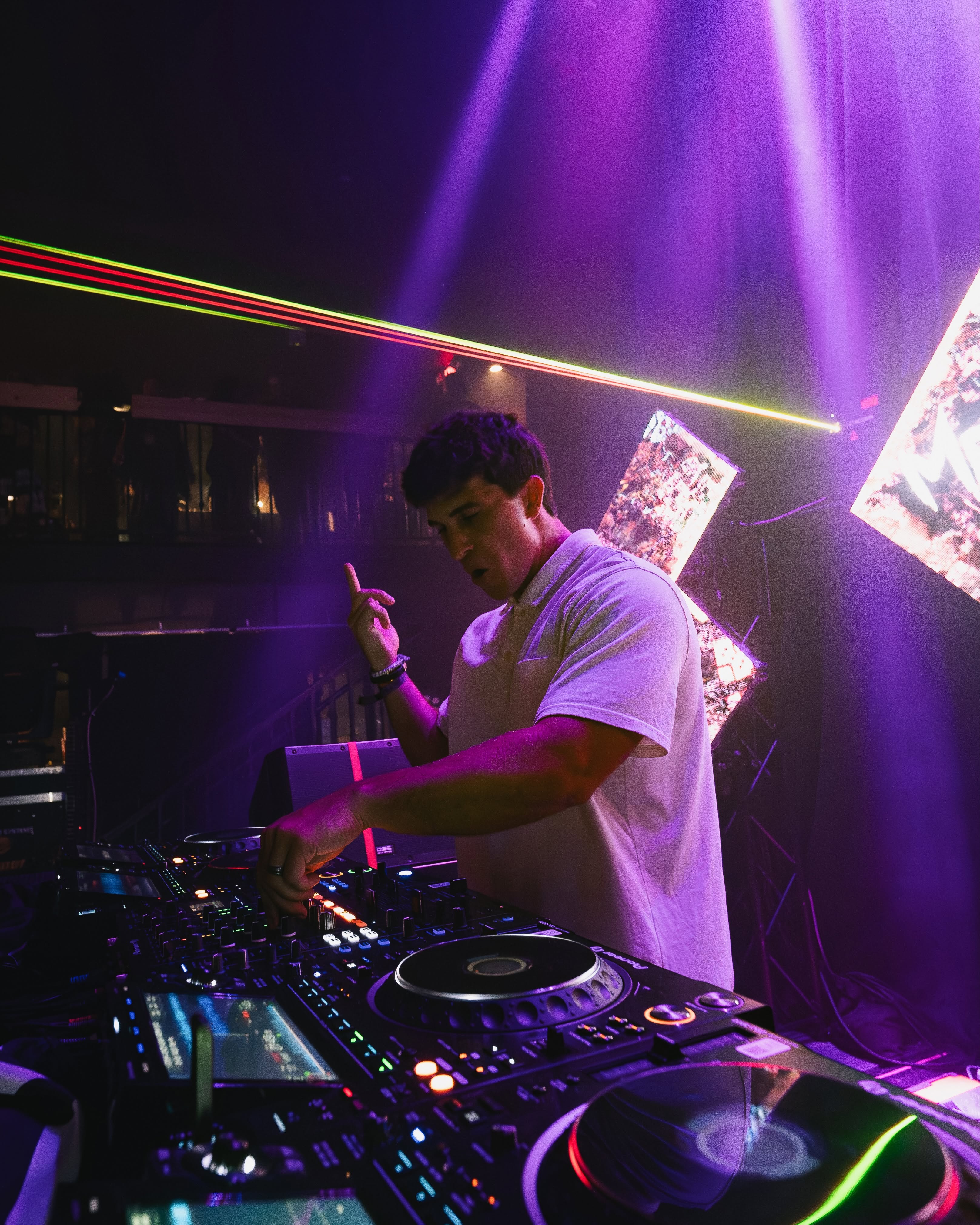 Headlining DJ performing with Pioneer CDJ decks and laser beams at McQueens