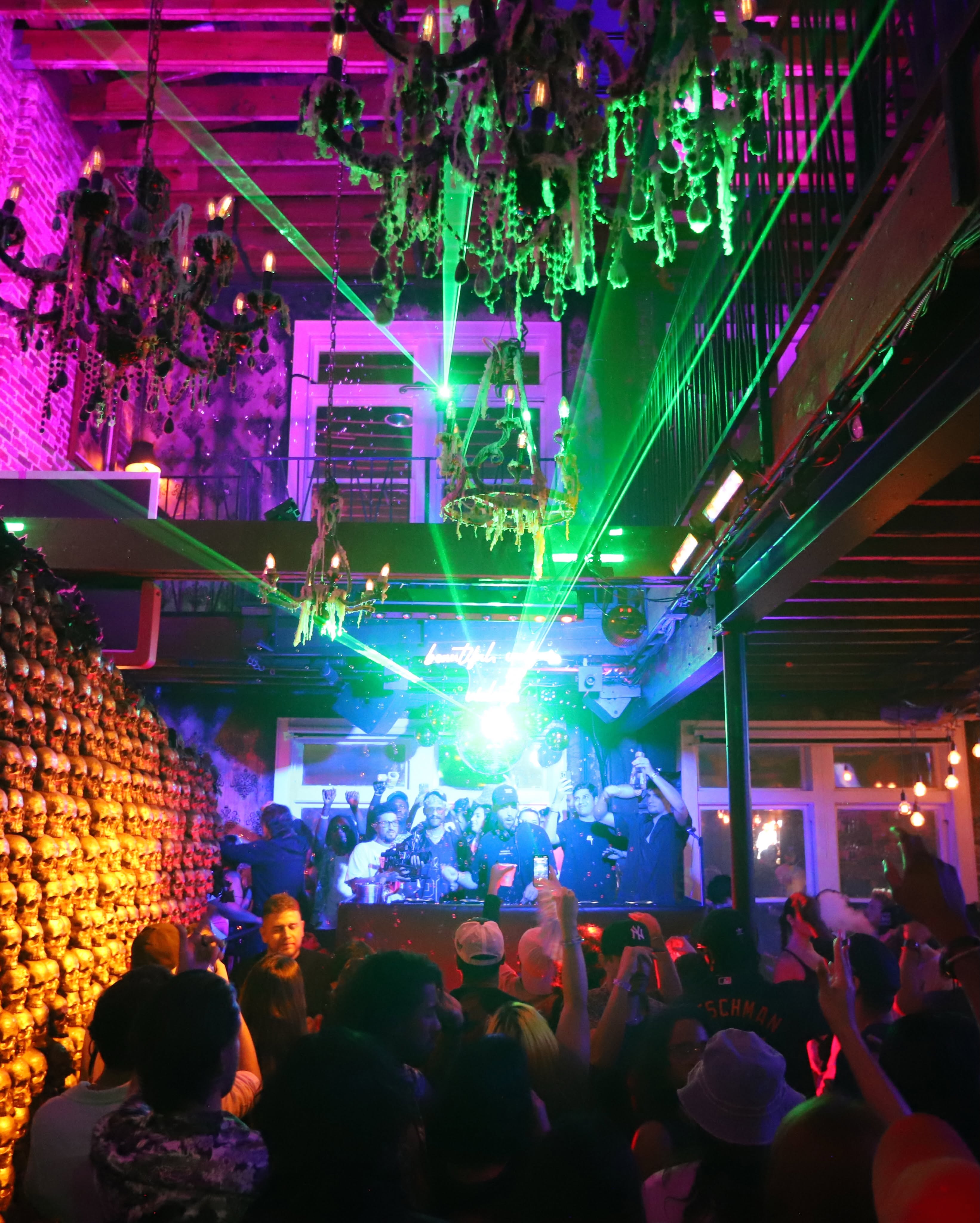 Emerald laser burst and golden skull wall illuminated during live DJ set