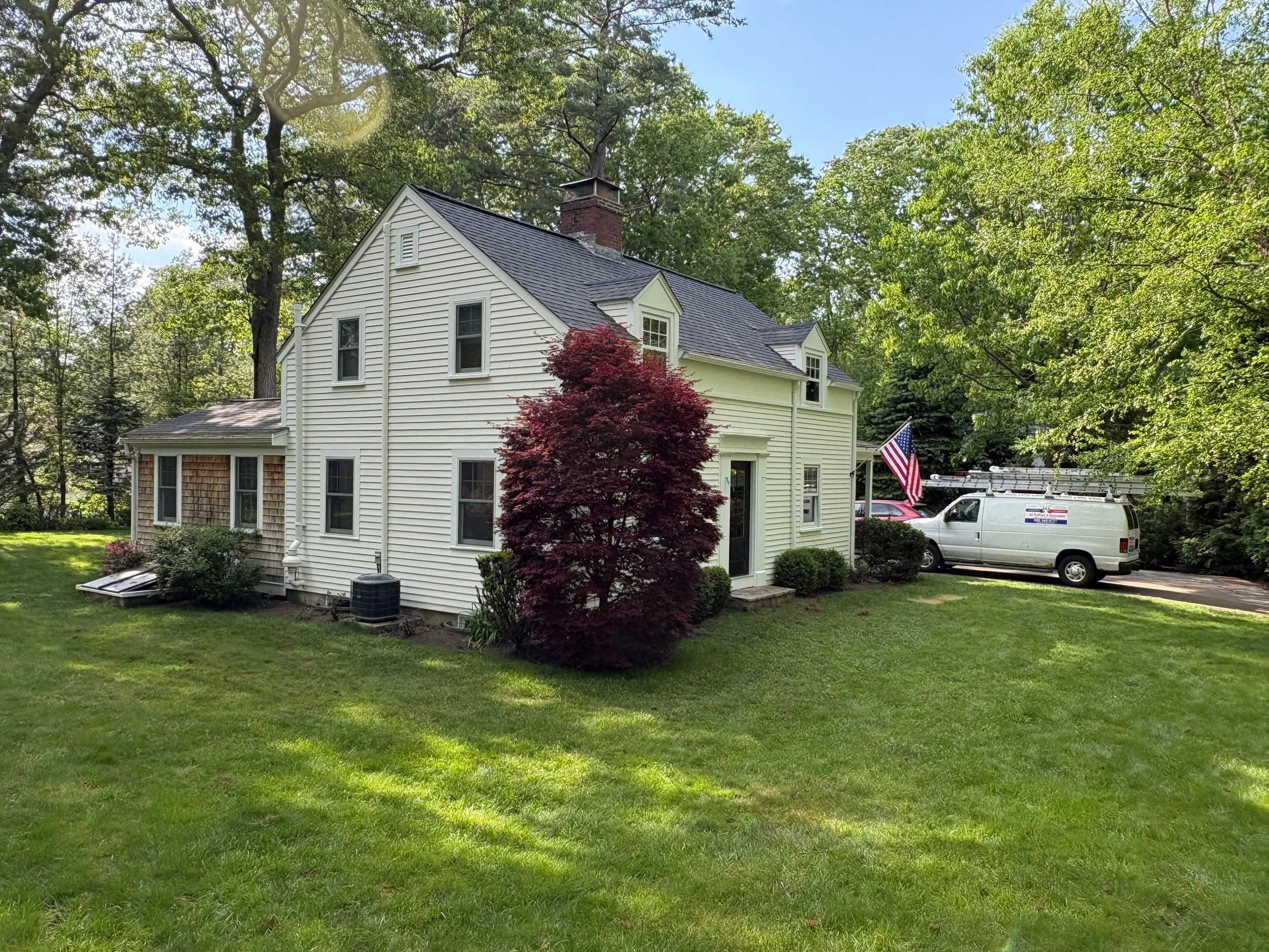 Completed exterior repaint of a classic New England Cape Cod home with off-white clapboard siding, dormers, and natural cedar shake wing