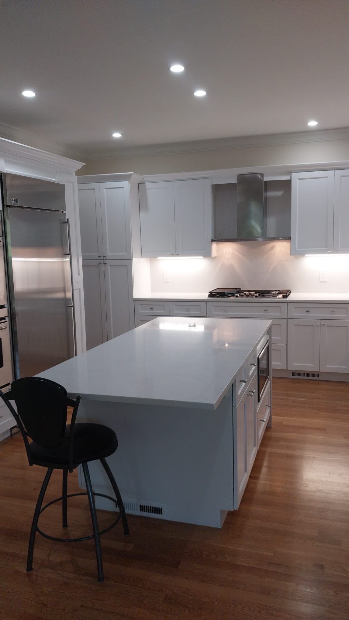 Completed kitchen renovation featuring large center island with built in microwave and under cabinet illumination