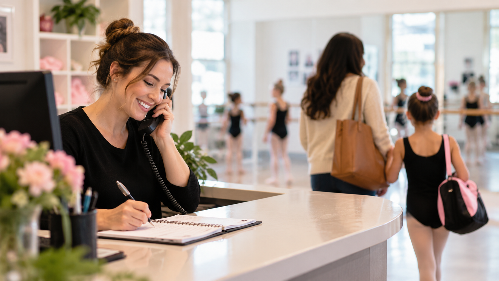 Studio front desk administrator answering an inquiry call as young dancers walk by