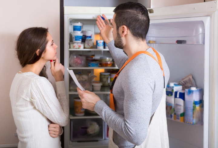 Technician and homeowner looking inside a refrigerator together during an appliance repair service in Millcreek, UT