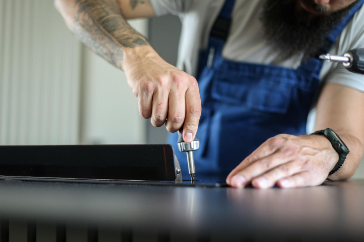 Close-up of a technician using a screwdriver to inspect and repair a kitchen appliance during an appliance repair service in Millcreek, UT