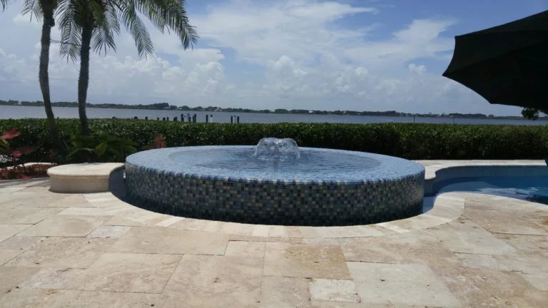 Custom circular glass mosaic spillover spa on travertine deck overlooking the river in Brevard County