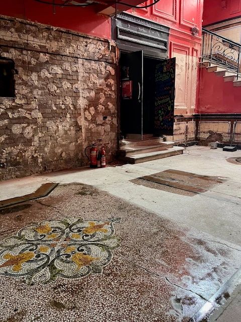 Old building interior with mosaic floor and exposed brick wall.