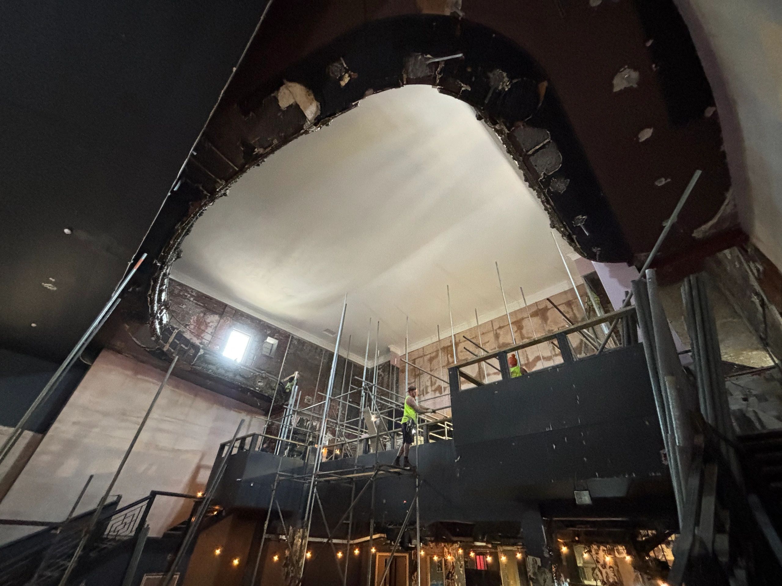 Interior view of a building under renovation with scaffolding and workers.