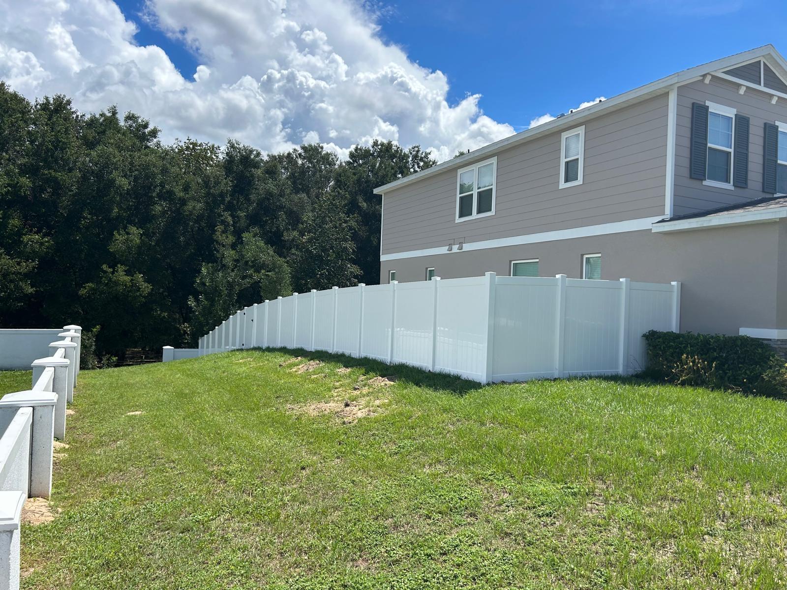 White vinyl privacy fence following sloped yard contour