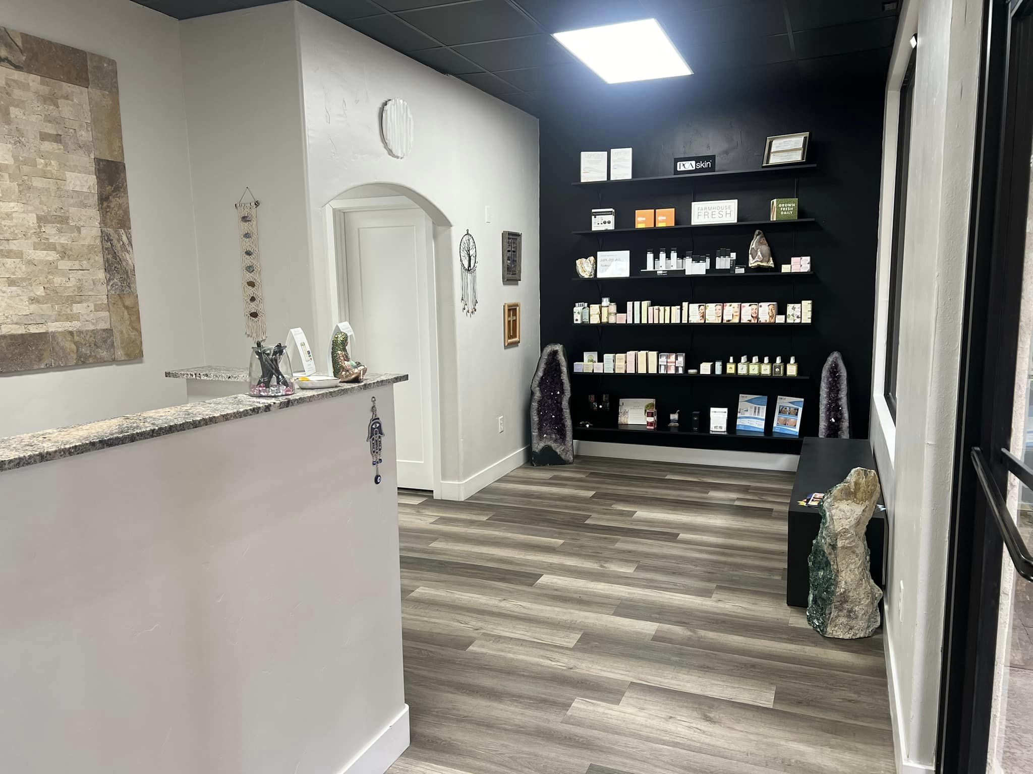 Bright welcoming reception area with modern wood flooring, granite reception desk, crystal accents, and retail wall