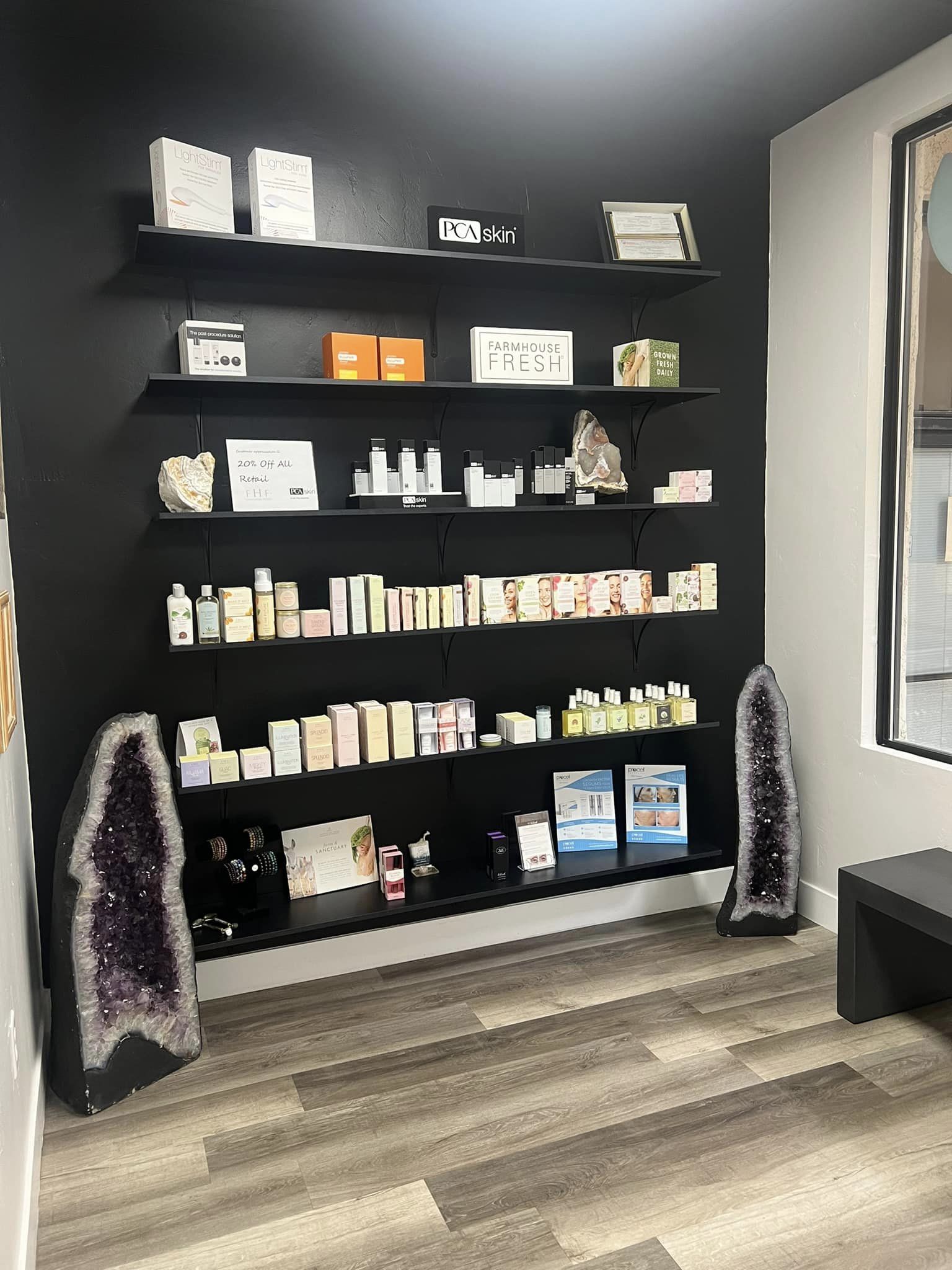 Black display shelves featuring PCA skin care, Farmhouse Fresh products, and large amethyst cathedral geodes