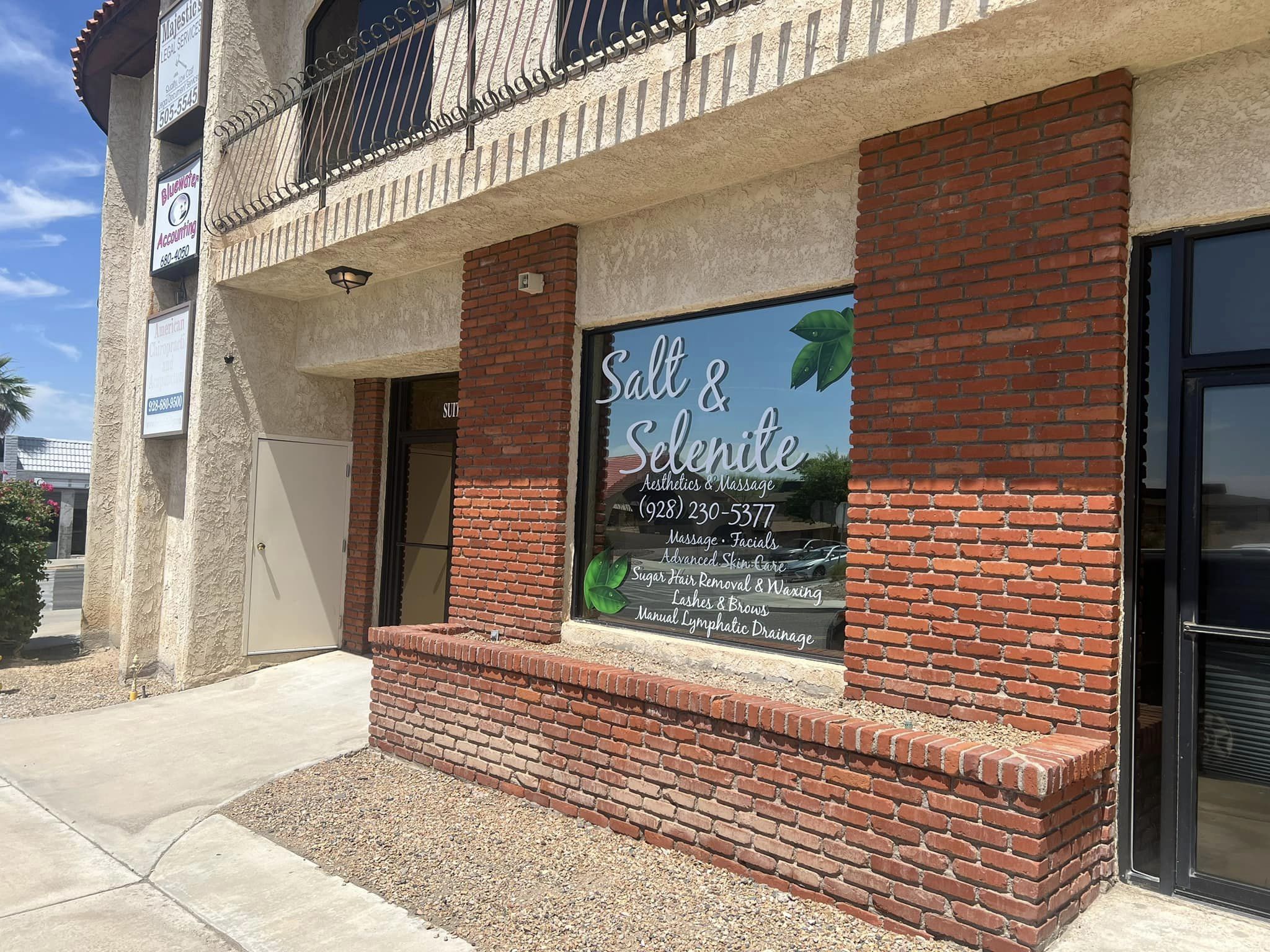 Exterior view of Salt and Selenite storefront with red brick accents and window lettering in Lake Havasu City