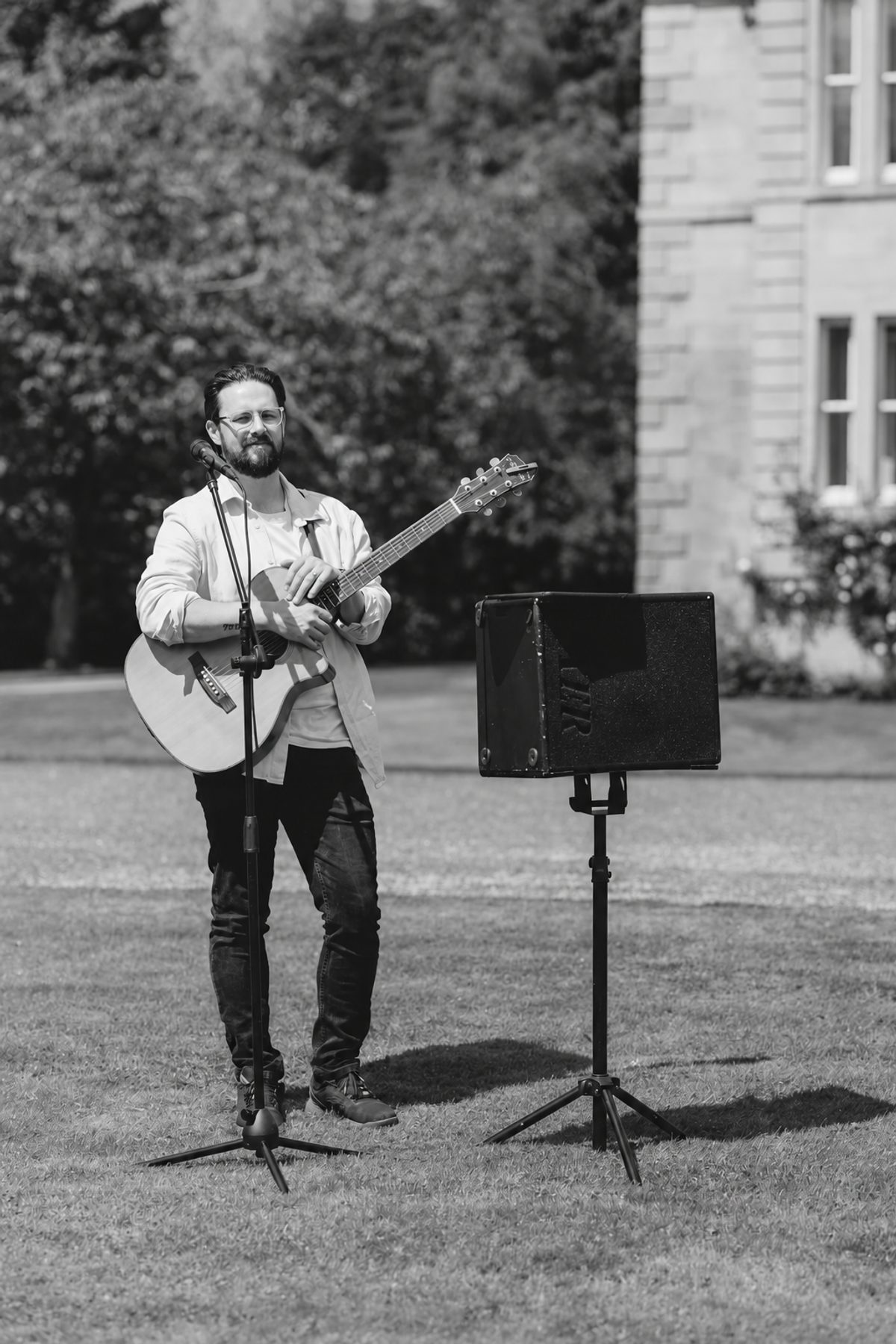 Stephen McPhee performing live with acoustic guitar on the lawn of an Aberdeenshire country estate