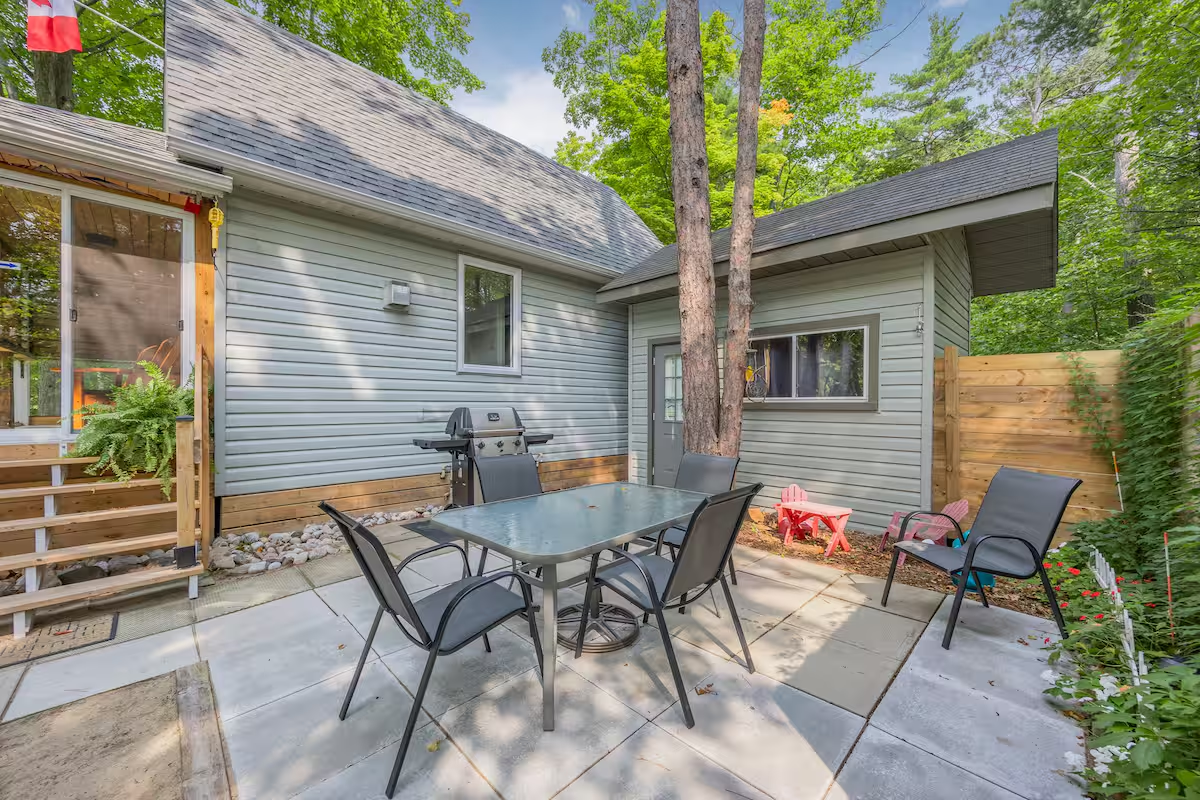 Private courtyard with outdoor dining table, patio chairs, barbecue, and mature tree canopy