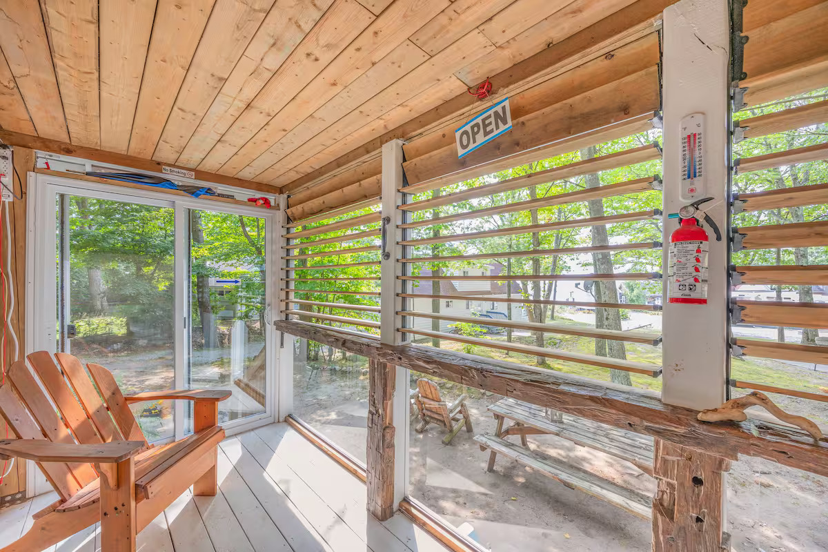 Enclosed porch solarium with wooden louvers and Adirondack chair overlooking Georgian Bay