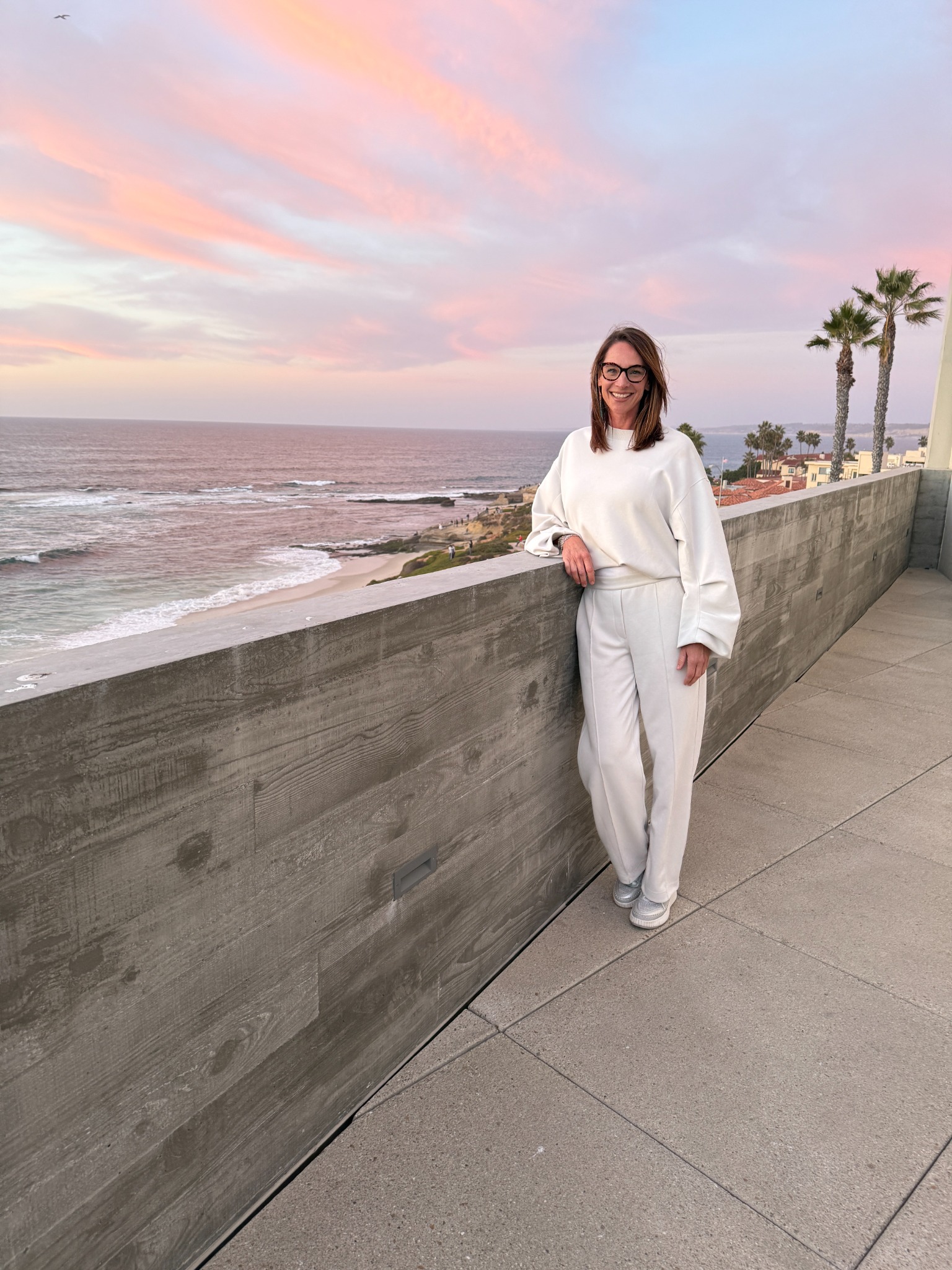 Cara Sansone in white on an ocean terrace at sunset