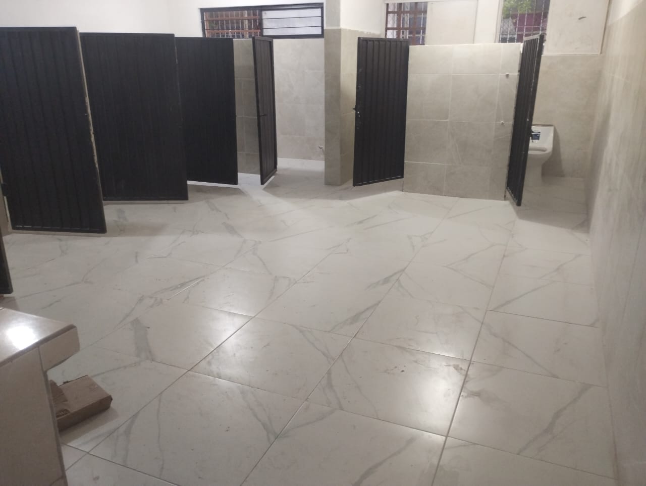 Instalación de piso cerámico pulido y muros en sanitarios escolares