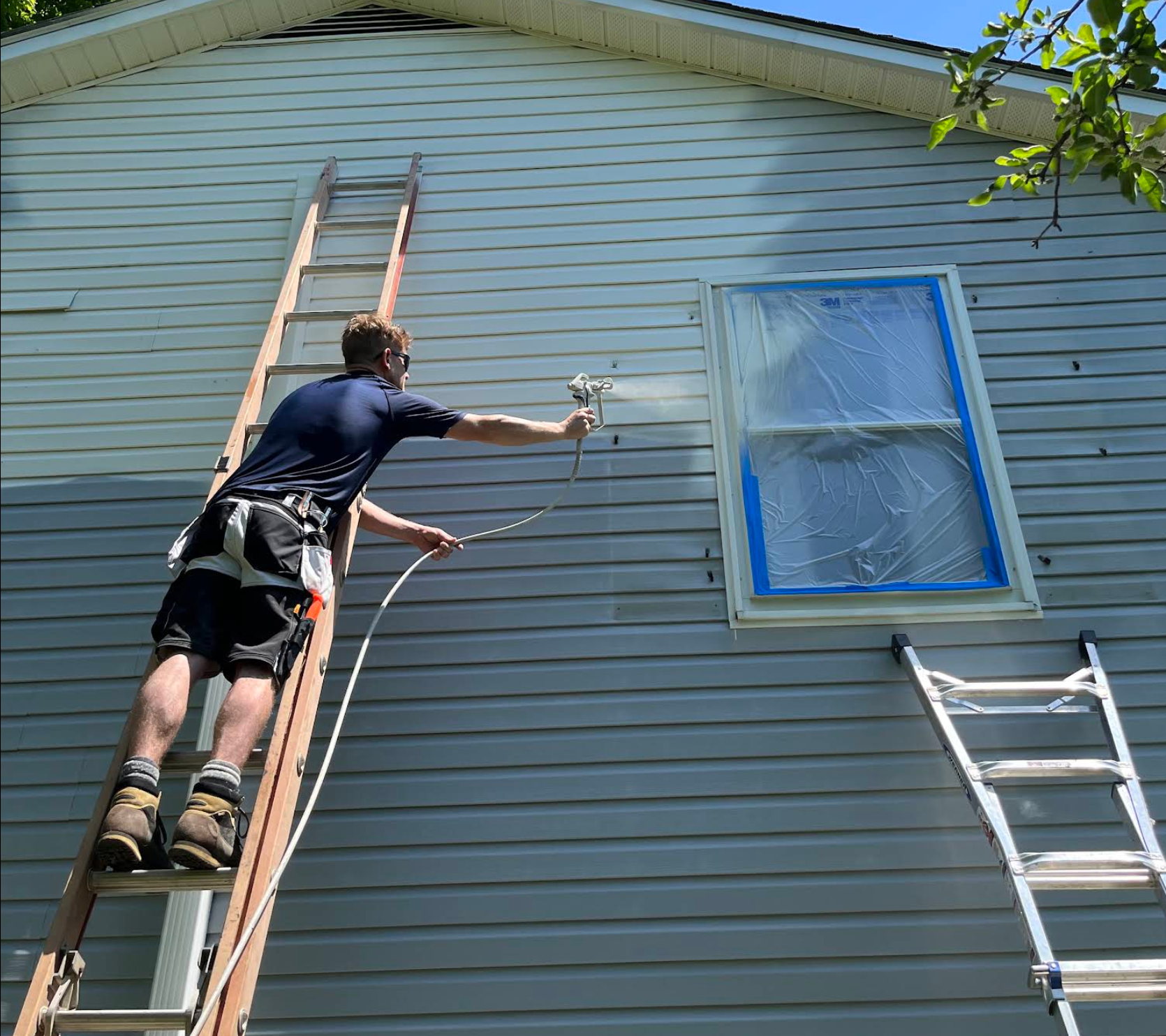 Painter on a ladder painting vinyl siding