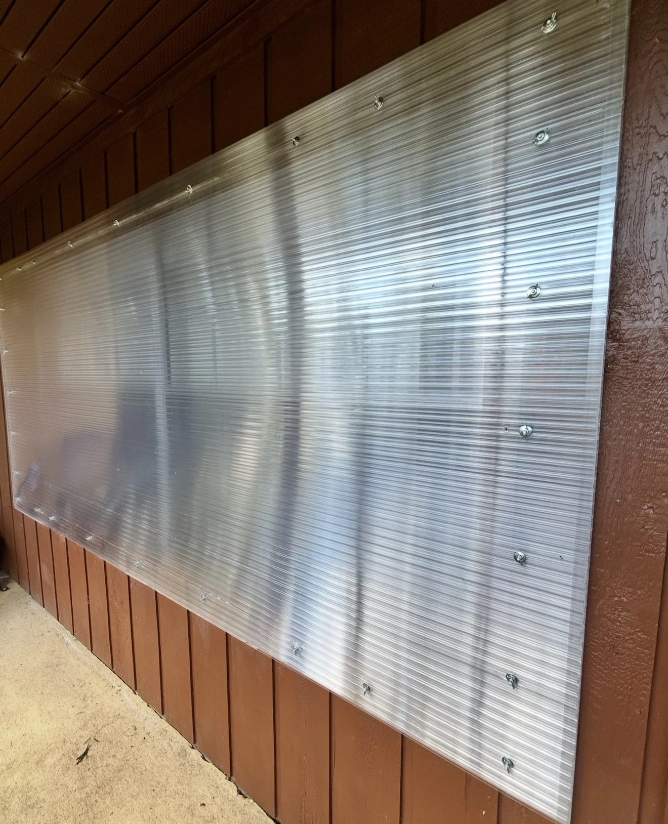 Exterior protective panel secured to building siding with heavy-duty mounting hardware