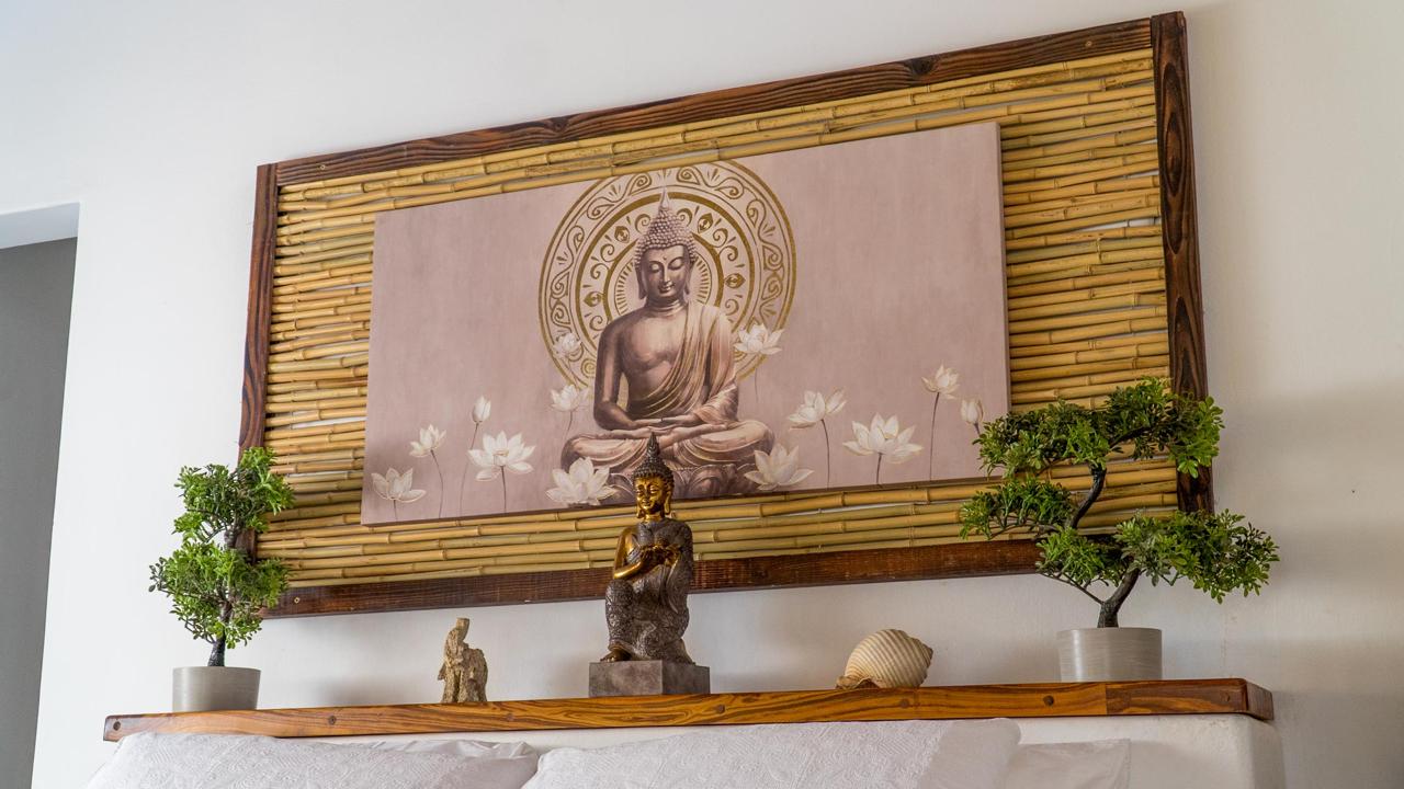Buddha and lotus artwork set against bamboo slats with handcrafted miniature Buddha and bonsai details at Bali Lodge