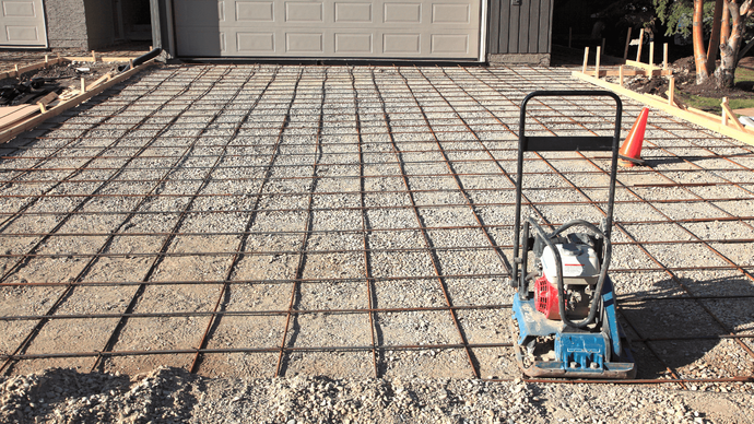 Prepared gravel sub-base with a tied grid of steel rebar laid out and ready for a concrete driveway pour by a contractor in Casas Adobes, AZ